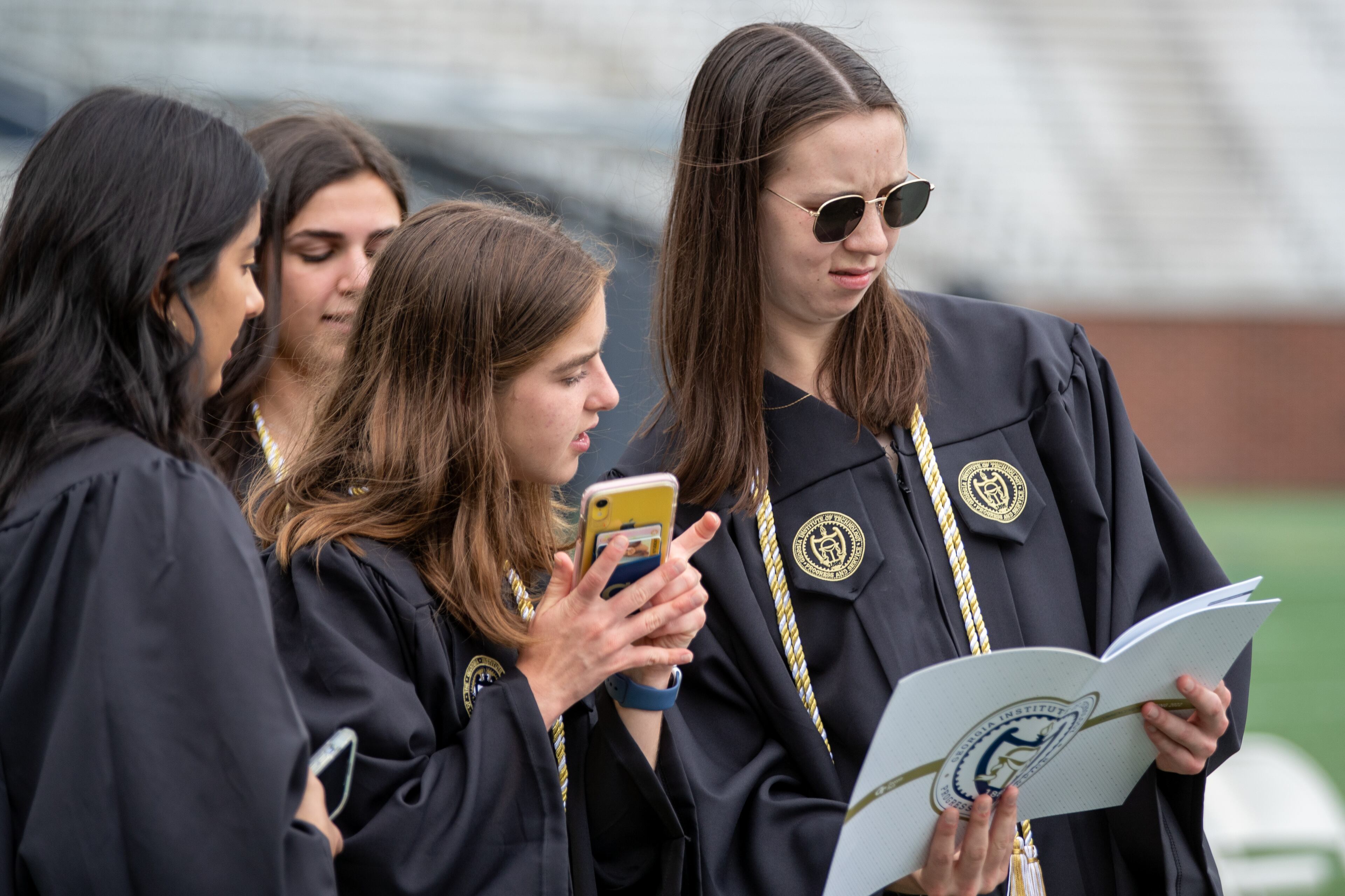 Graduating students look over the program before the start of the Georgia Institute of Technology's afternoon Commencement Ceremony at Bobby Dodd Stadium on Saturday, May 7, 2022. (Steve Schaefer / steve.schaefer@ajc.com)