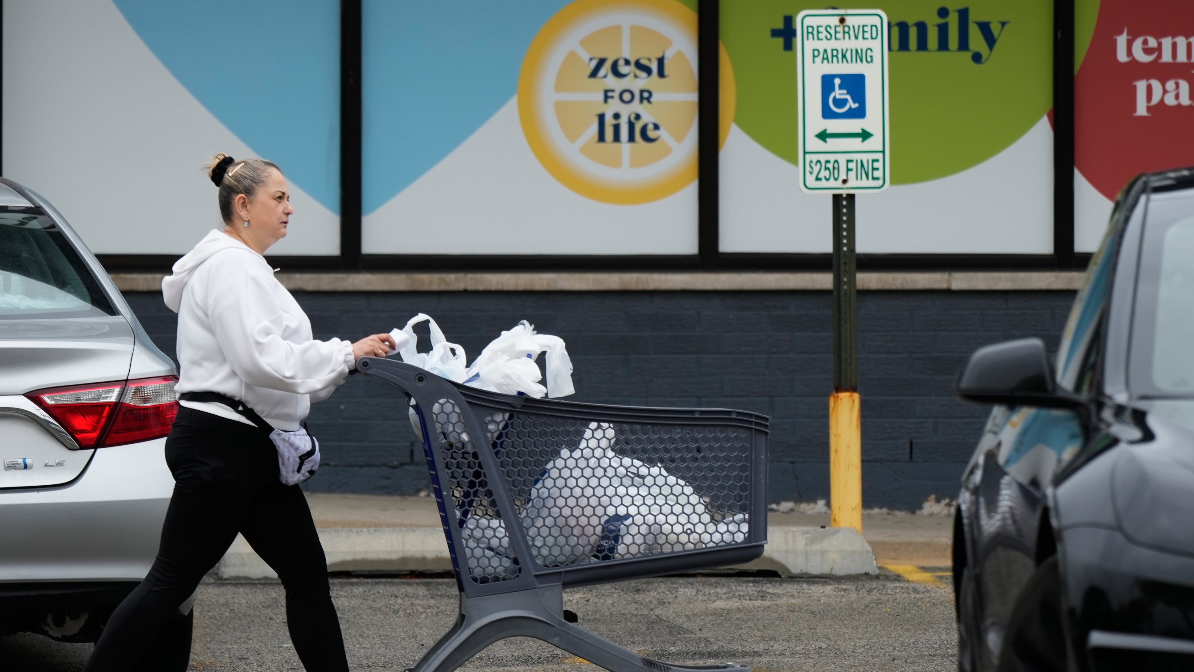 A woman pushes a shopping cart as she leaves a grocery store in Arlington Heights, Ill., Wednesday, Sept. 30, 2026. (AP Photo/Nam Y. Huh)