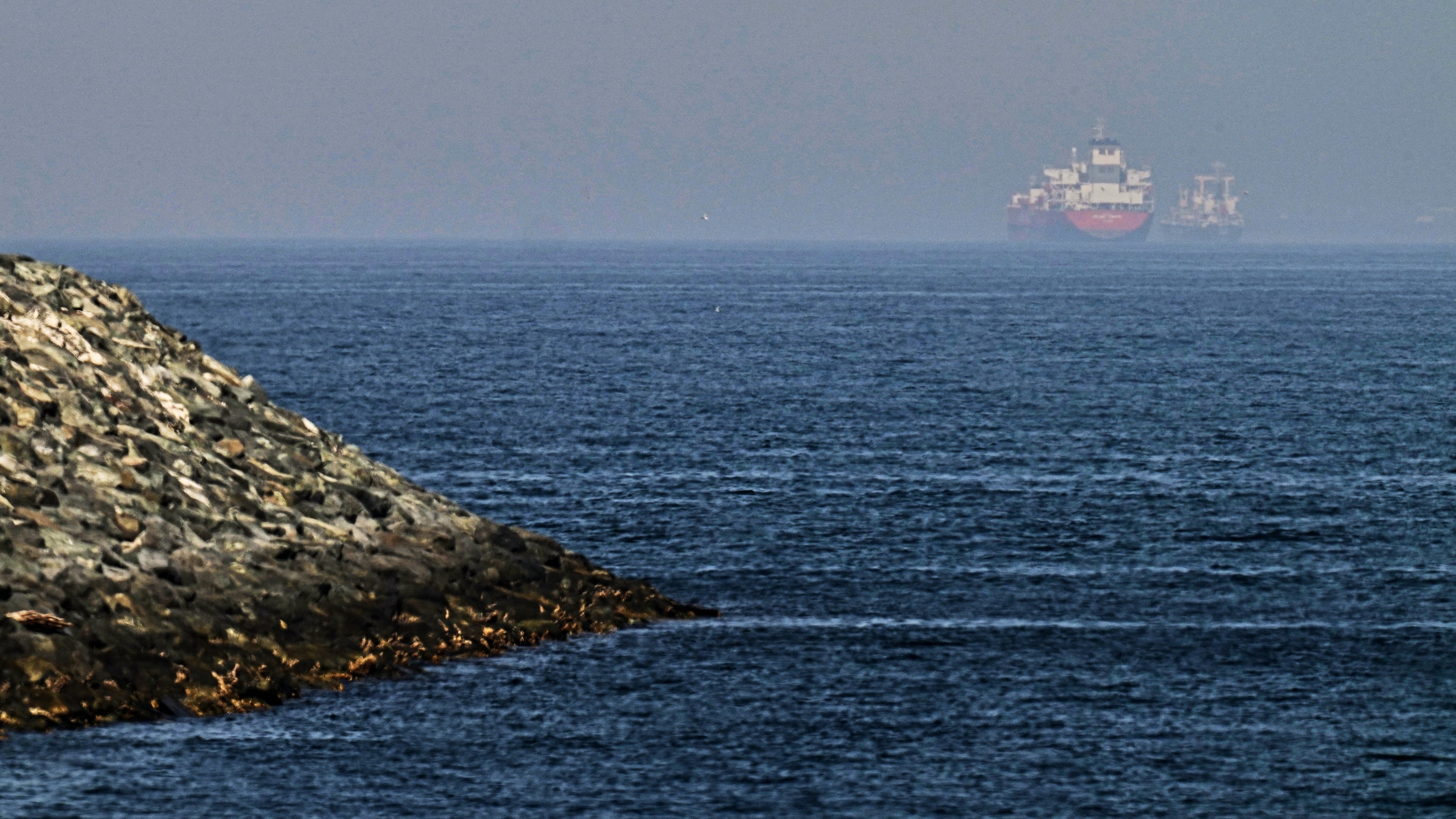 Cargo ships are seen at sea near the Strait of Hormuz, as viewed from a rocky shoreline near Khor Fakkan, United Arab Emirates, Friday, May 1, 2026. (AP Photo/Fatima Shbair)