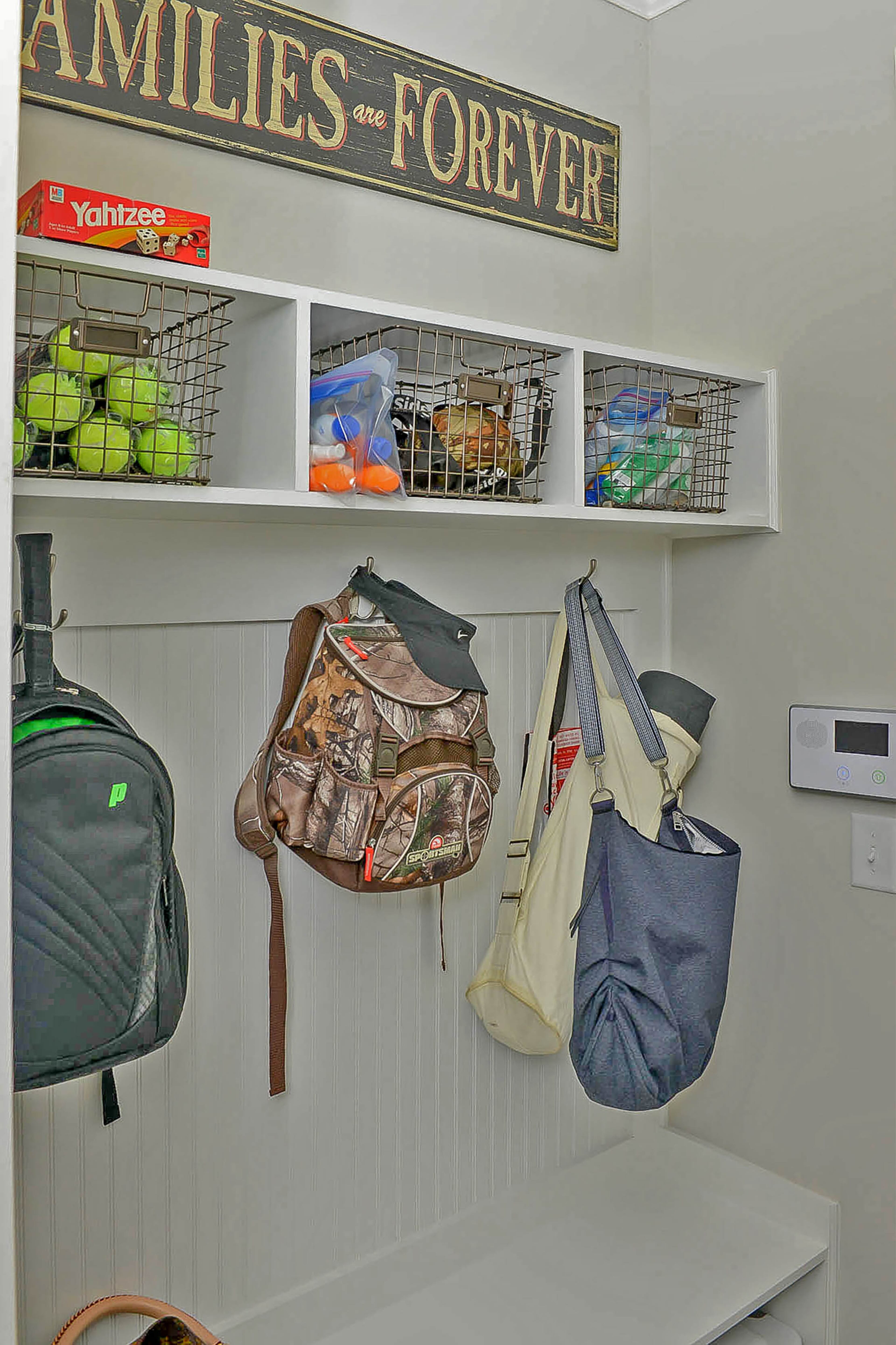 Sports equipment, backpacks and other gear are contained in wire baskets and on hooks in the mudroom.
