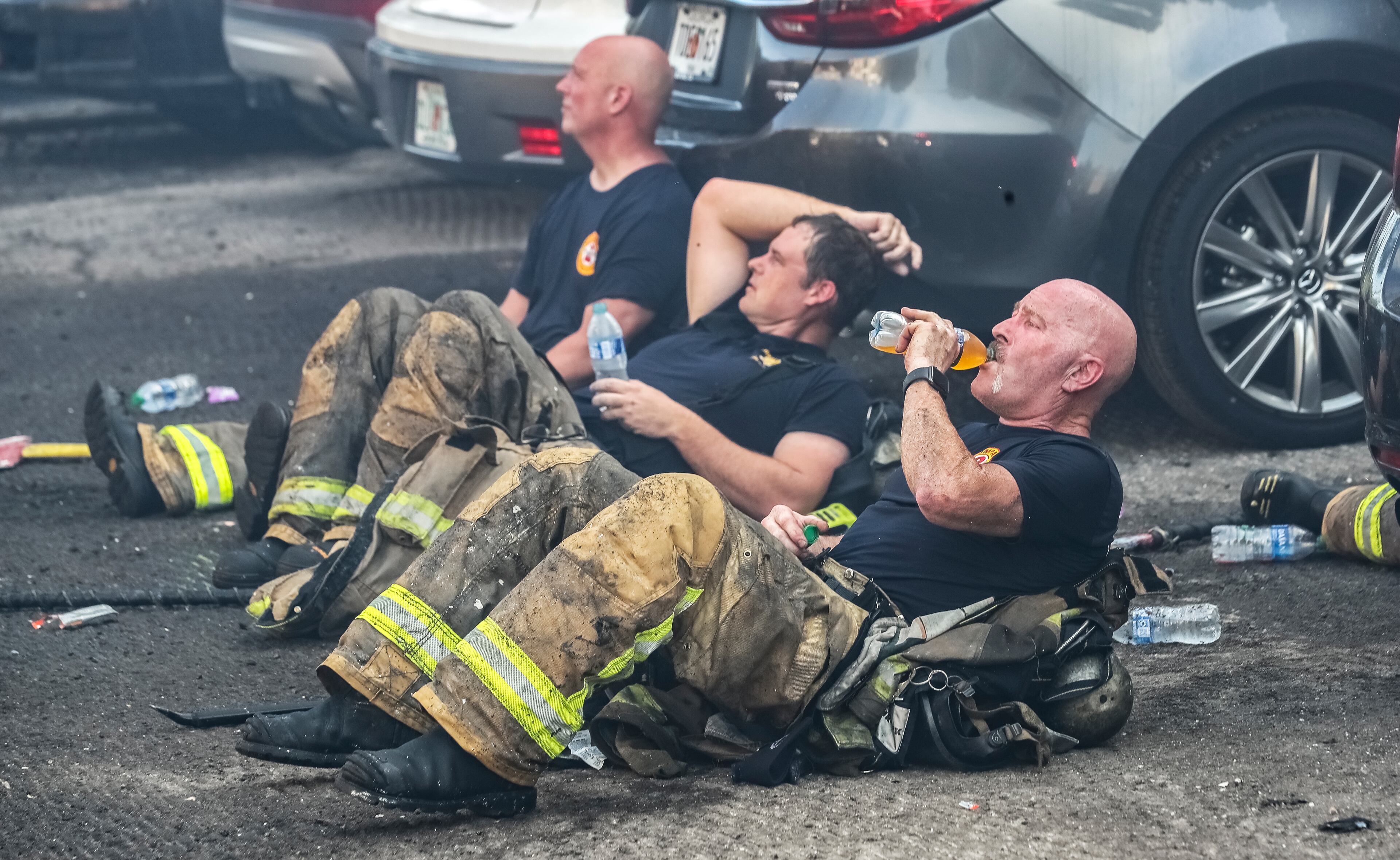 July 18, 2022 DeKalb County: Left to right - Tommy Hicks, Jason Rutland and Boyd Franklin of Truck-2 rehab from the heat and fighting fire. All residents of a Brookhaven apartment building were able to escape their homes safely when a massive blaze broke out early Monday morning, July 18, 2022. No injuries were reported in the fire at the Evergreen Lenox Park apartments, which sent huge flames and smoke high into the air above nearby Roxboro and North Druid Hills roads at the start of the morning commute. Everyone inside the building evacuated before the first crews arrived about 6:30 a.m., thanks in large part to the effort of one man. Yusuf Thorne was on his way into work when he heard a subtle cracking sound and spotted the fire coming from an apartment on the third floor. Thorne said he called 911, connected with a dispatcher, and immediately hung up to begin knocking on his neighbors’ doors. He escorted one woman to safety and went back again to try to wake another neighbor. “He eventually came out,” Thorne said. “I was going to have to kick the door down if they didn’t get out of there.” Thorne said he had to continue knocking on doors as the fire spread. According to fire Capt. Jaeson Daniels, the flames reached an attic space and eventually destroyed several third-floor units. “It started on the third floor so the fire didn’t have very far to travel to get to the attic, really saving the apartments on the bottom from fire damage,” Daniels said. “But unfortunately, the top apartments had severe fire damage.” He estimates about 18 families will lose their homes and need the assistance of the American Red Cross for temporary lodging and other emergency needs. Fire crews dug through the debris Monday morning to learn the extent of the damage. Investigators have not determined the fire’s cause or exact origin. (John Spink / John.Spink@ajc.com)