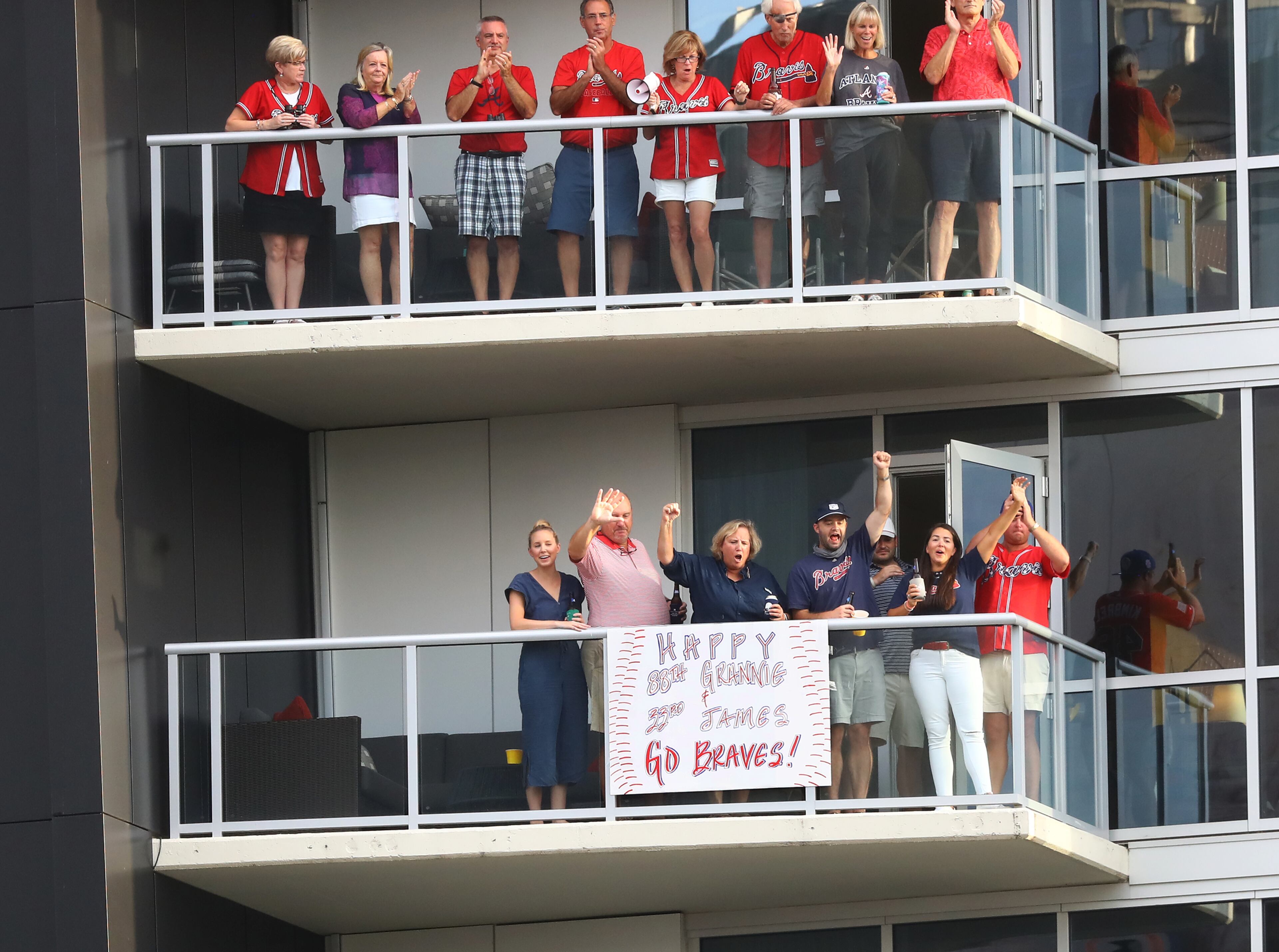 Atlanta Braves fans cheer their team from the balcony of their room at the Omni Hotel just outside Truist Park during the first inning against the Philadelphia Phillies in a MLB baseball game on Sunday, August 23, 2020 in Atlanta. Curtis Compton ccompton@ajc.com