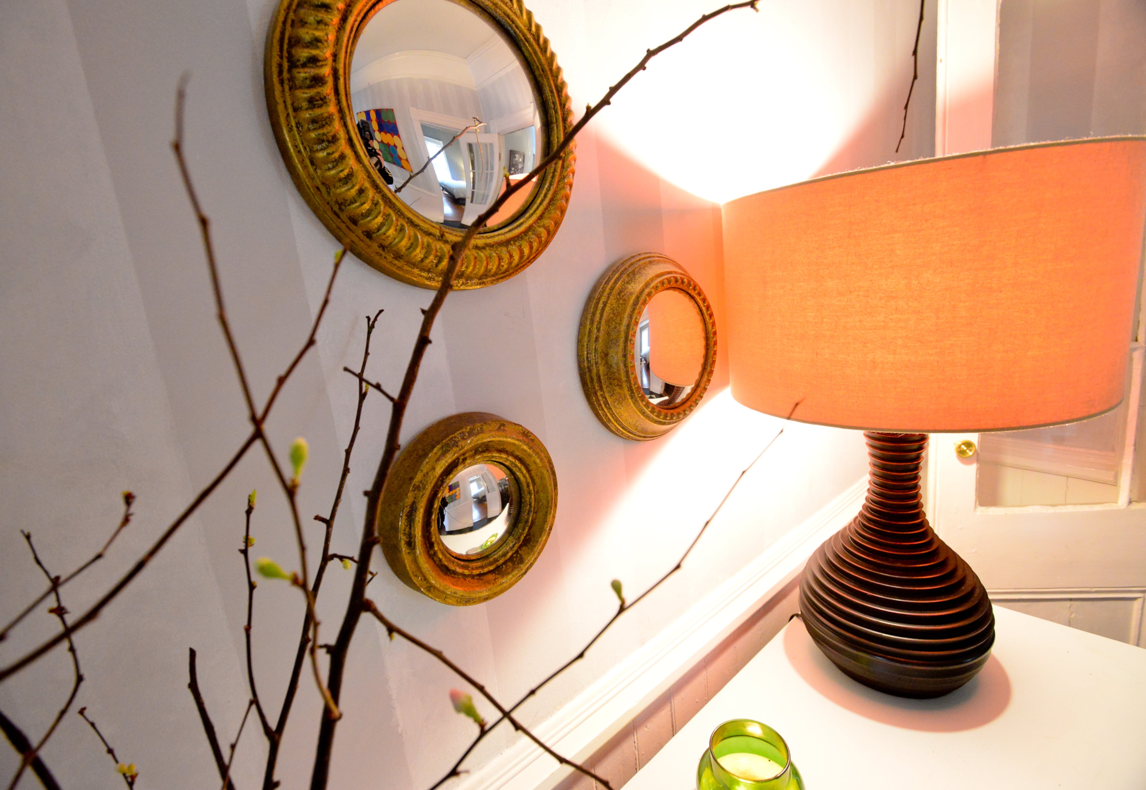 A lamp, which Nick bought for Kendall as a birthday present from West Elm, and real cherry tree limbs from Floral Park Market decorate a white chest that held her grandparents' record player. The display and the round gold mirrors - which are from Scott's Antique Markets -- are in the entryway leading from the front door.