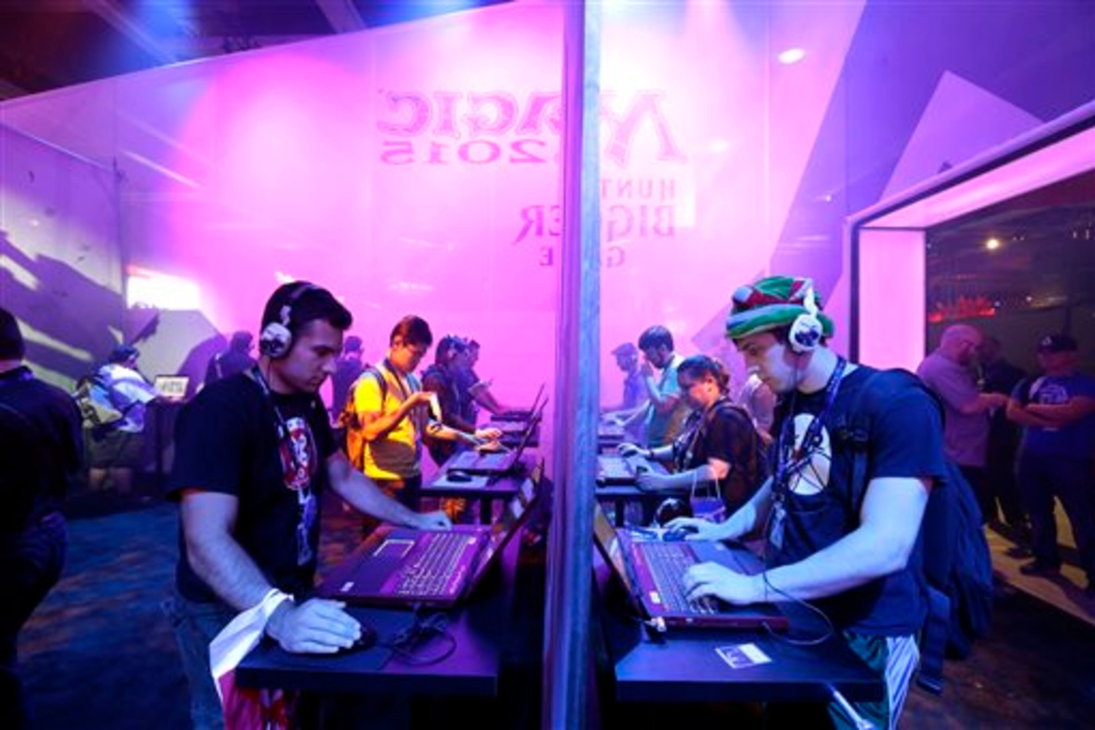 Video gamers play Magic 2015 - Duels of the Planeswalkers from Wizards of the Coast on both sides of a partition, Friday, Aug. 29, 2014, in a booth at the Penny Arcade Expo, a fan-centric celebration of gaming in Seattle. The event is expected to be attended by roughly 85,000 gamers and will include concerts, game tournaments and previews of upcoming titles. (AP Photo/Ted S. Warren)