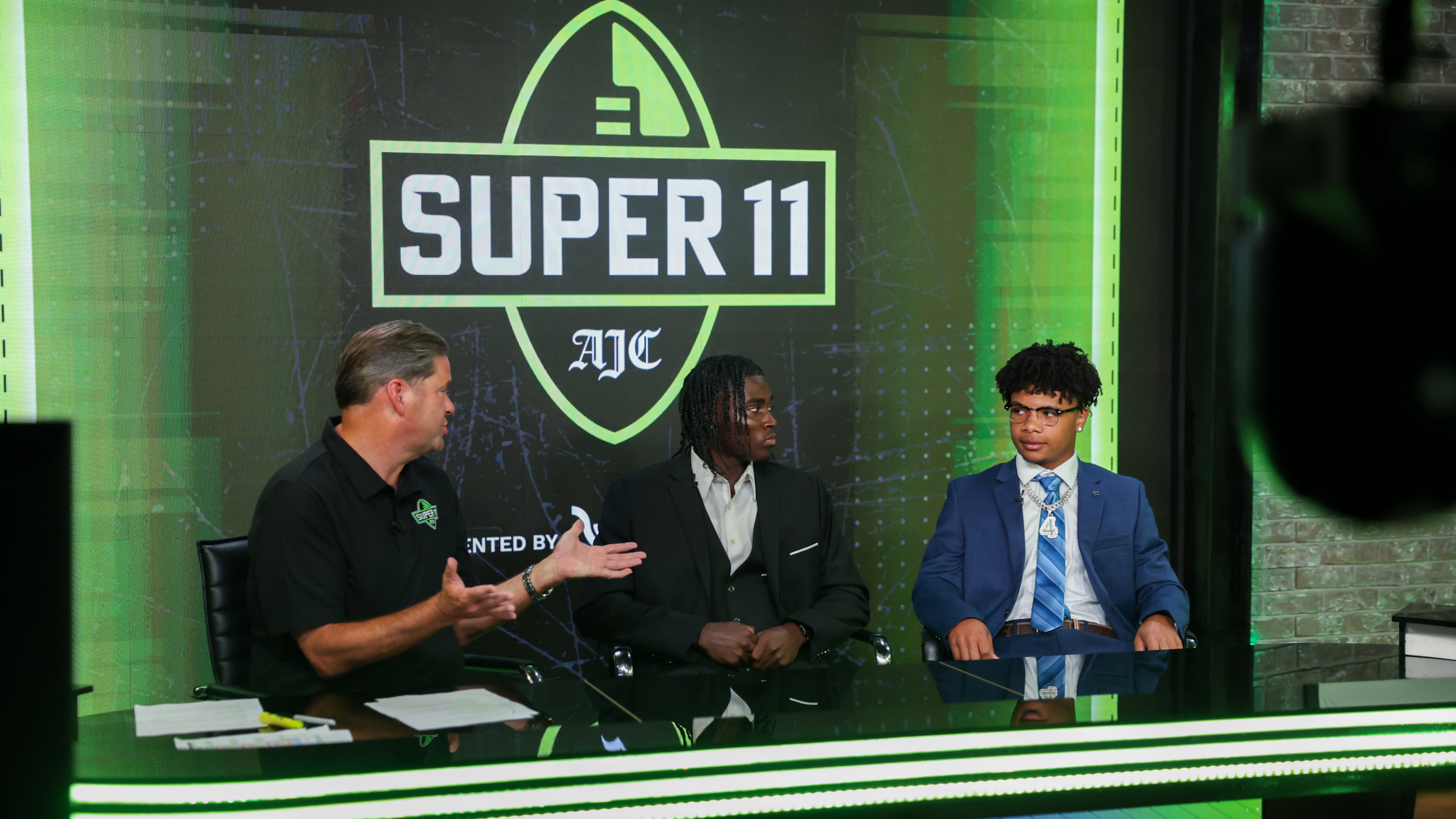 (L-R) DawgNation’s Brandon Adams interviews Creekside’s Gary Walker and Valdosta’s Marquis Fennell during the taping of the Super 11 reveal show at Score ATL in Roswell on Aug. 3, 2026. (Arvin Temkar/AJC)