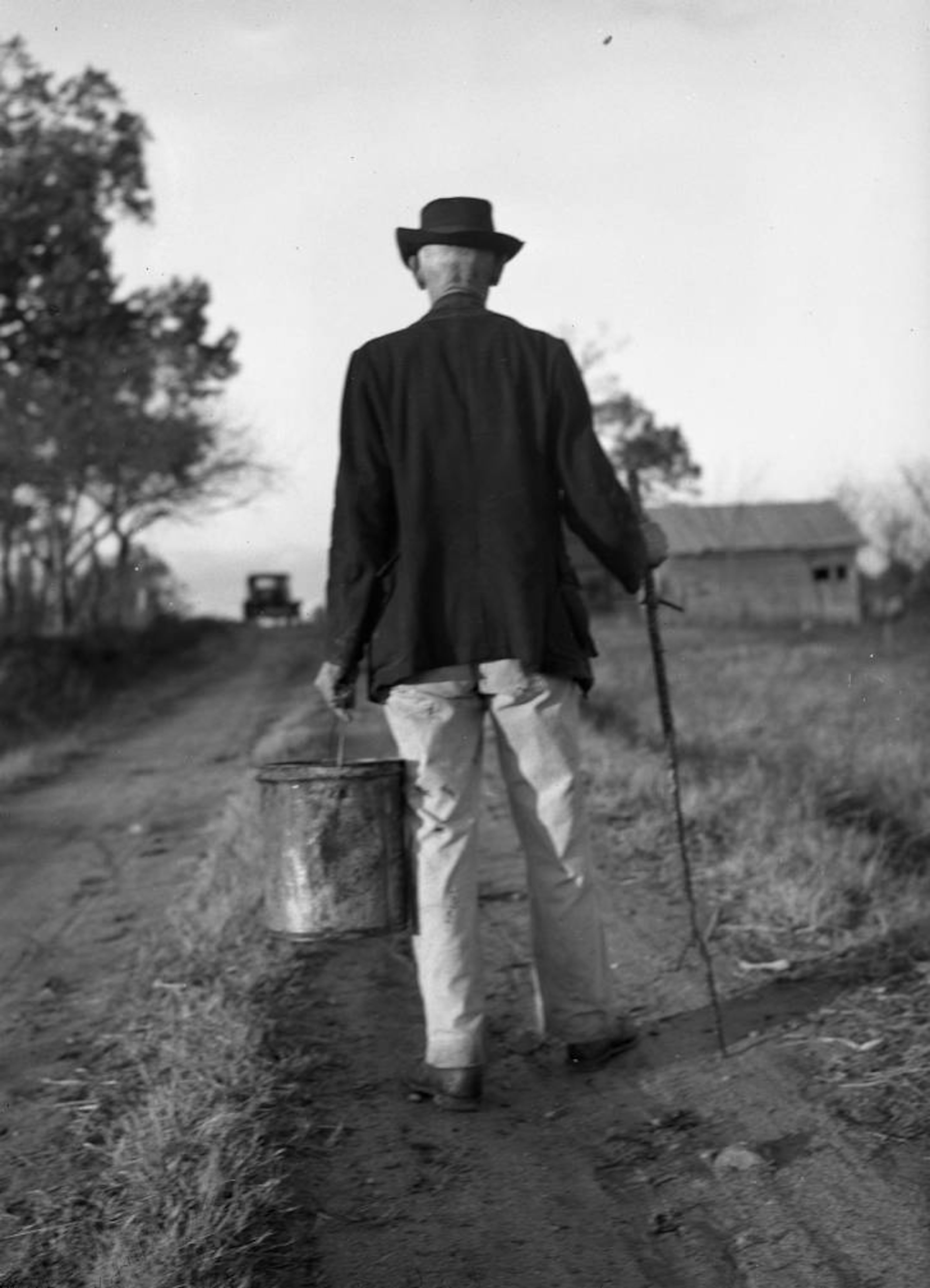 Dec. 23, 1945 -- An elderly man walks down a rural road with a bucket of home-brewed persimmon beer. AJC PHOTO ARCHIVES
