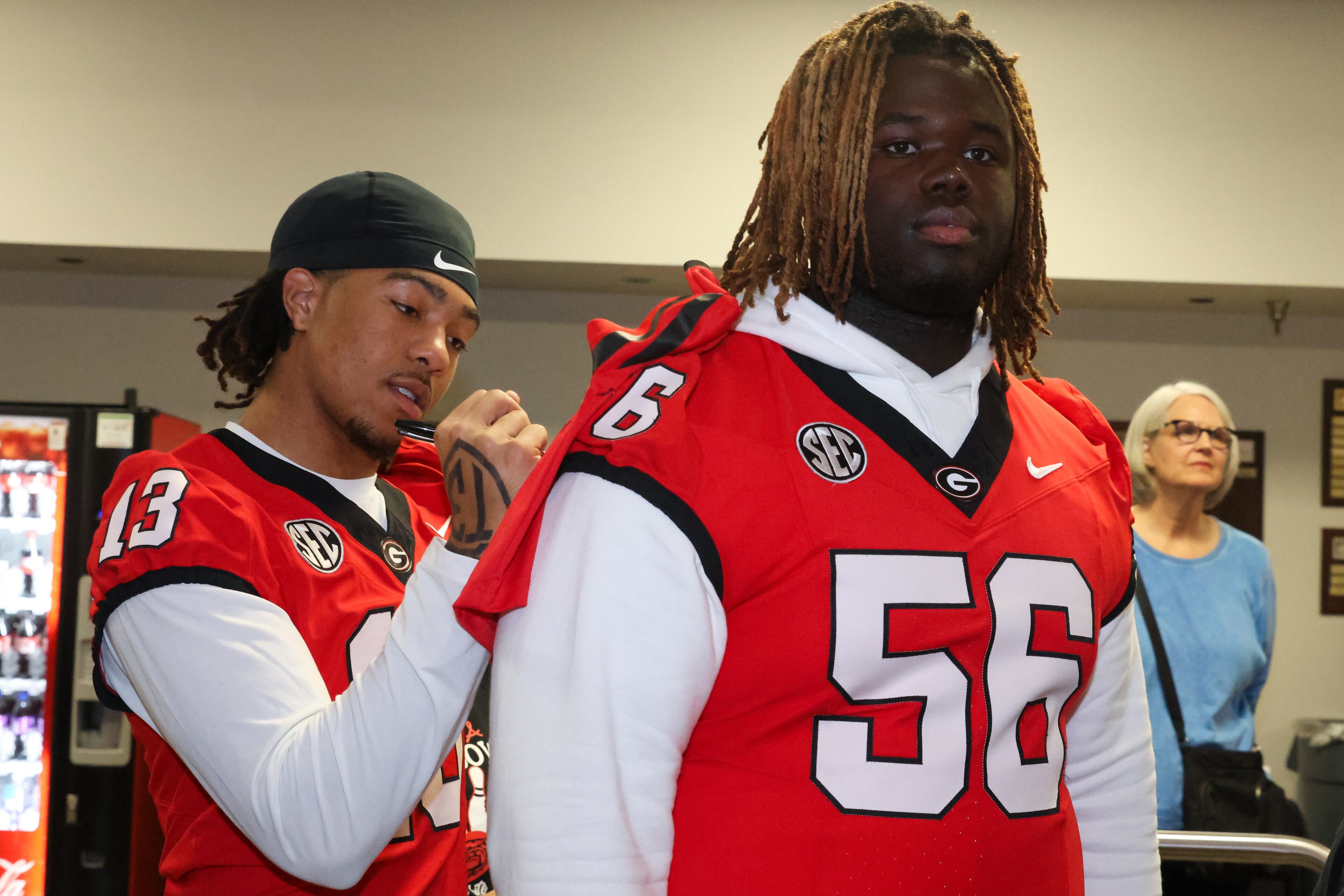 UGA wide receiver Tyler J. Williams (13) signs a jersey on the back of offensive lineman Micah Morris (56) during the third annual Chick-fil-A Dawg Bowl fundraiser for Parkinson’s and Crohn’s disease research at Showtime Bowl in Athens on Wednesday, Oct. 22, 2025. (C.J. Bartunek for the AJC)