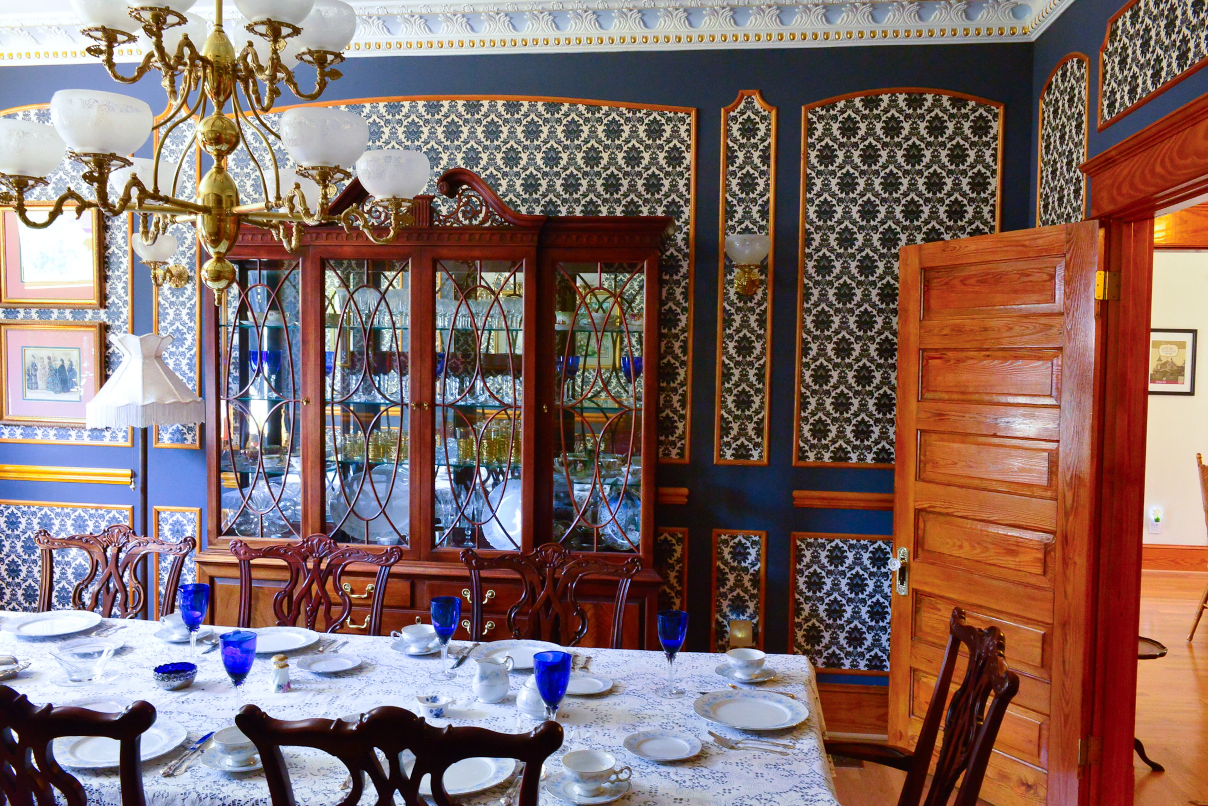 Special occasions and holidays are celebrated in the dining room, which was inspired by the look of a lighting showroom in Atlanta that had wallpaper panels and narrow trim. Homeowner Mike Dufano sketched out the layout for the blue and cream-colored wallpaper and fit the design around their china cabinet, sconces and other items. He also made the chandelier.