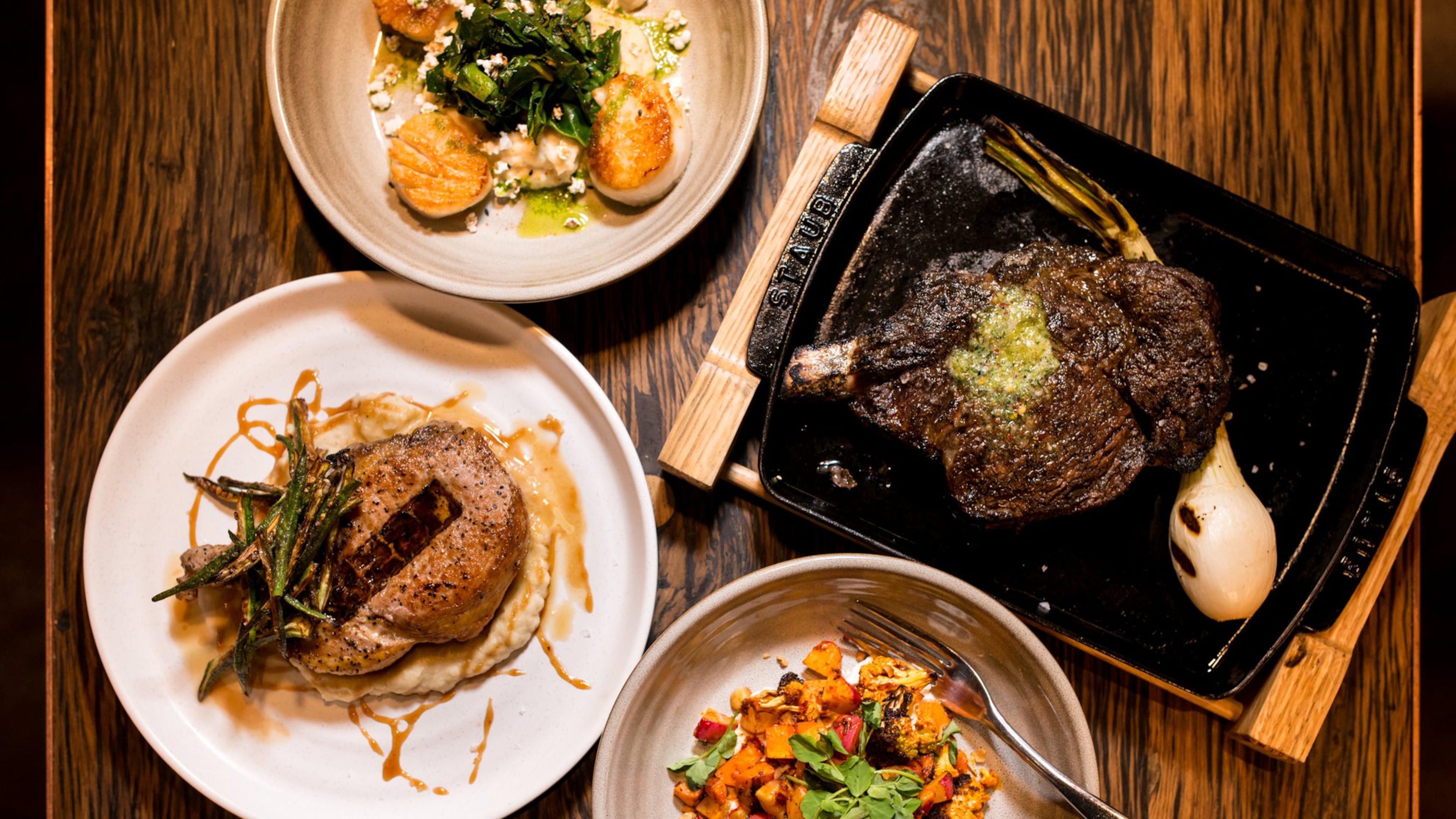ear Pan Seared Diver Scallops, Cowboy Ribeye, Harissa Roasted Winter Veggies, and Thompson Farms Pork Chop. Photo credit- Mia Yakel.