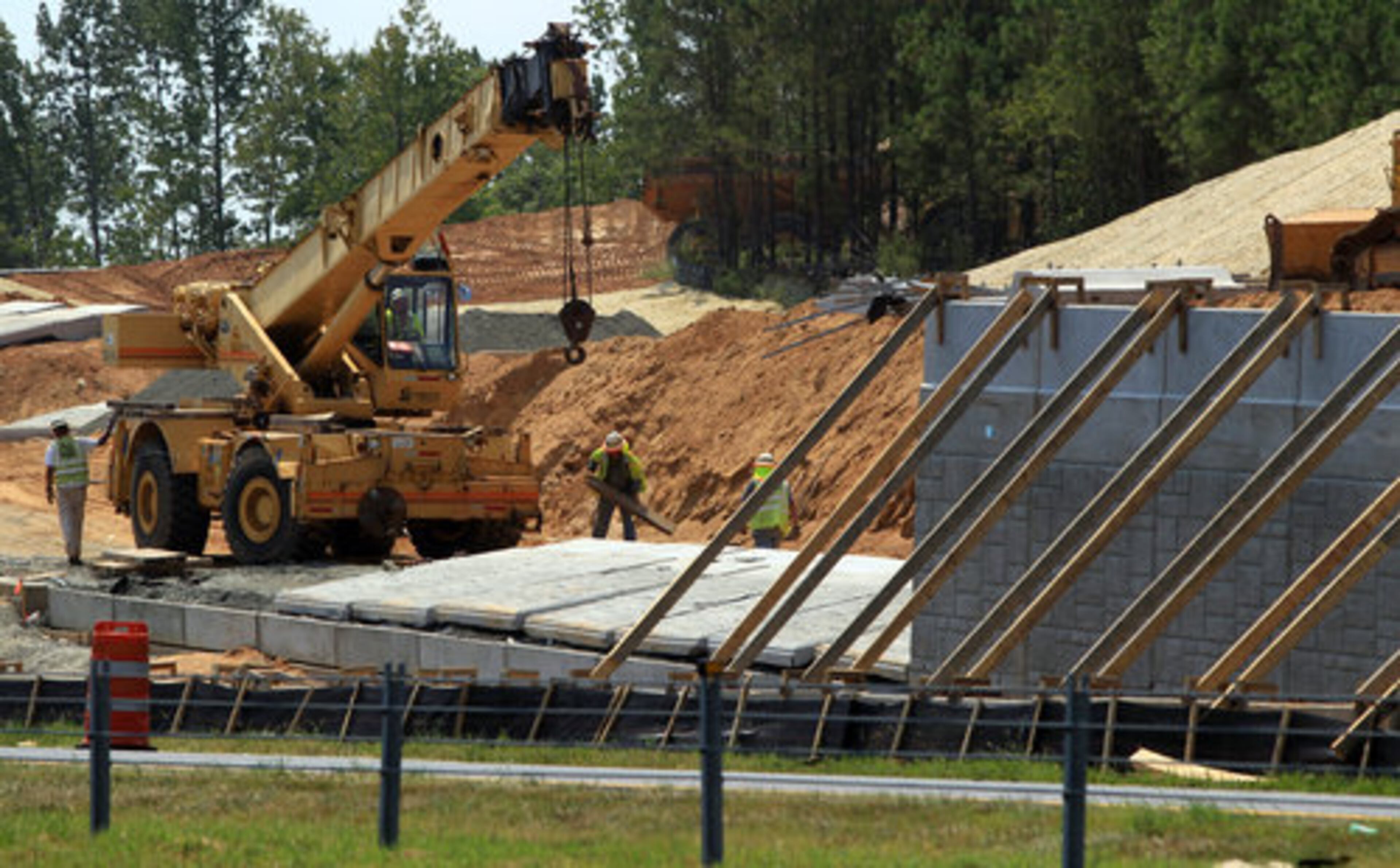Workers begin to repair a collapsed retaining wall on part of a new interchange under construction on I-575 in Woodstock after several 16,000 pound sections fell on Thursday.