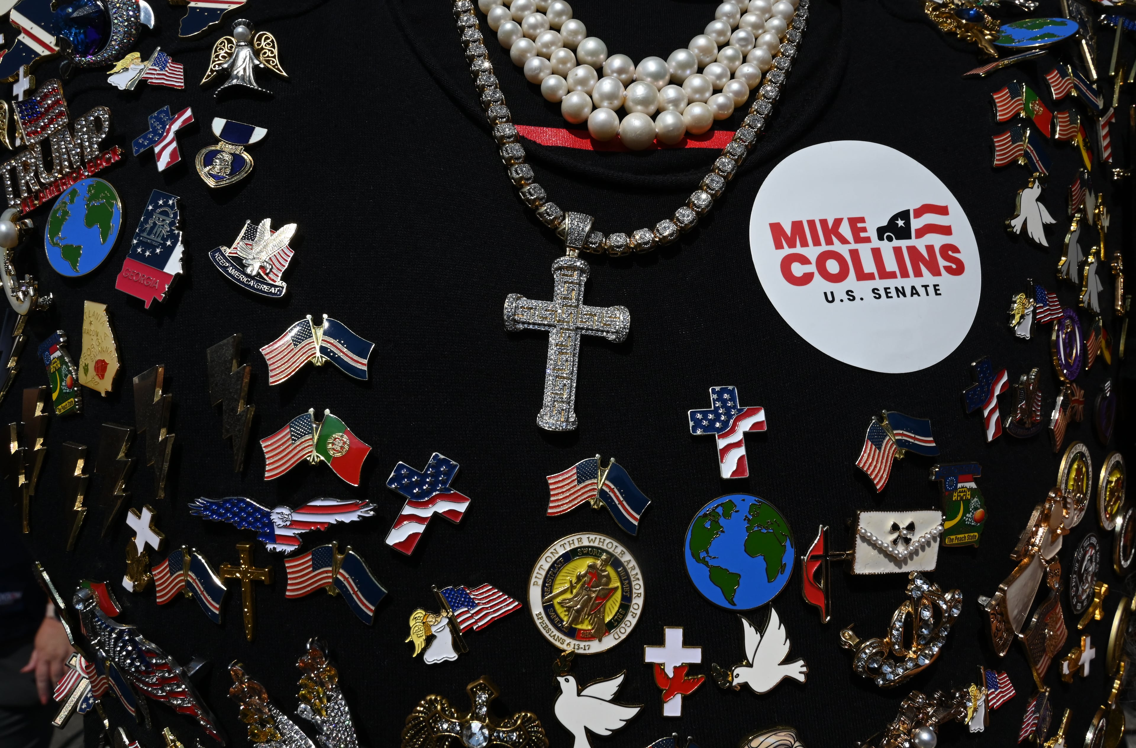 A supporter decorates his T-shirt with pins before a campaign rally at Dalton Municipal Airport on Friday, Oct. 16, 2026, in Dalton. (Hyosub Shin/AJC)