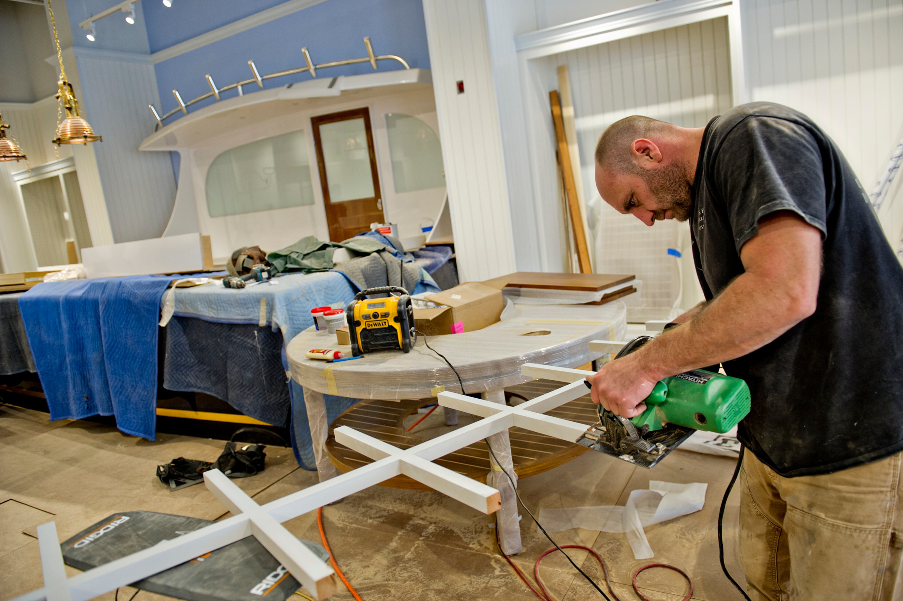 Shawn Schledorn cuts wood with a saw inside the Vinyard Vines store.