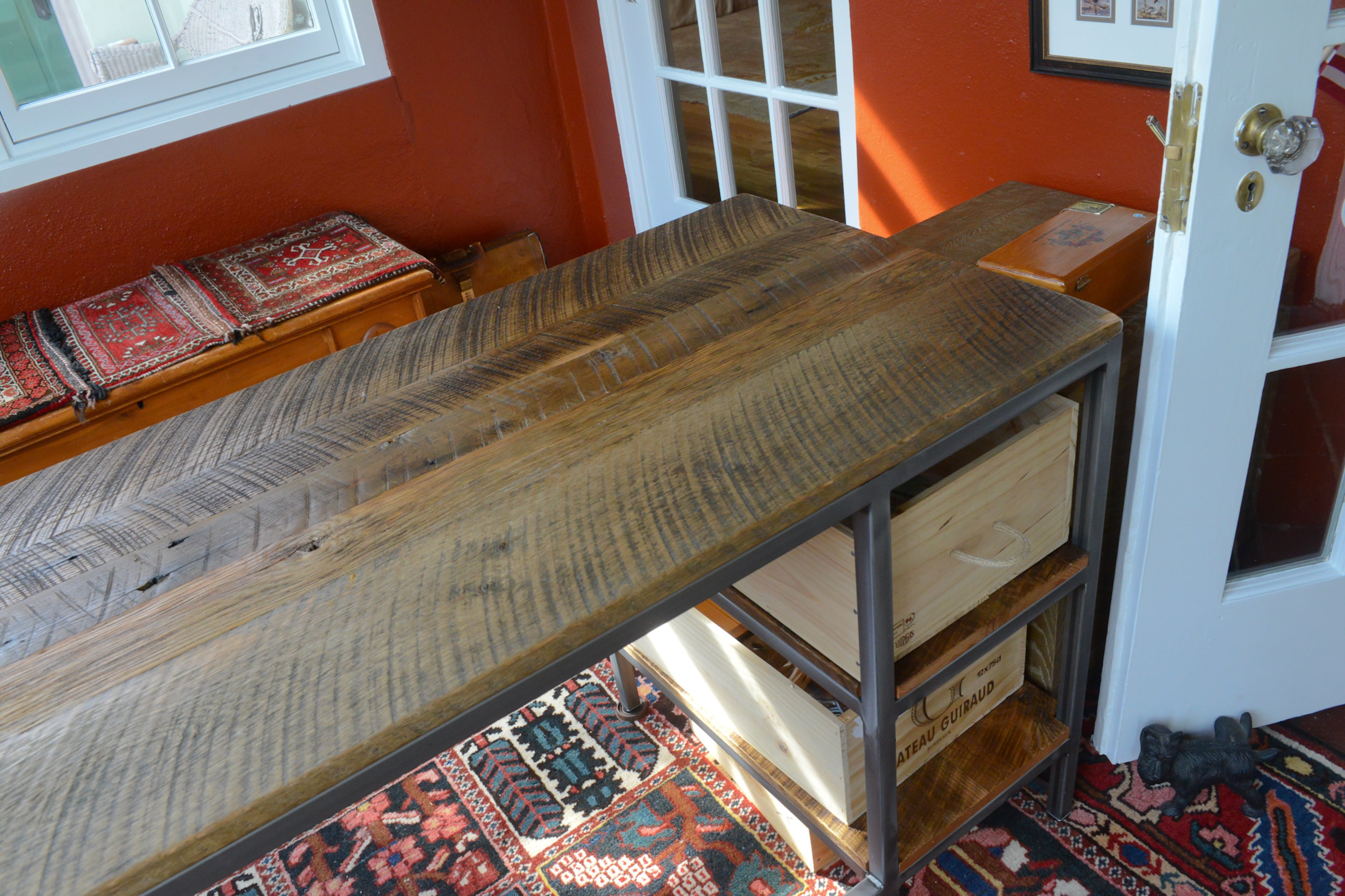 A rustic industrial desk and brightly colored rug anchor the home office space in the former sunroom. The desk, made out of distressed oak from a barn in North Carolina, is a product of No Longer Bound, an organization that helps people recovering from drug and alcohol abuse.