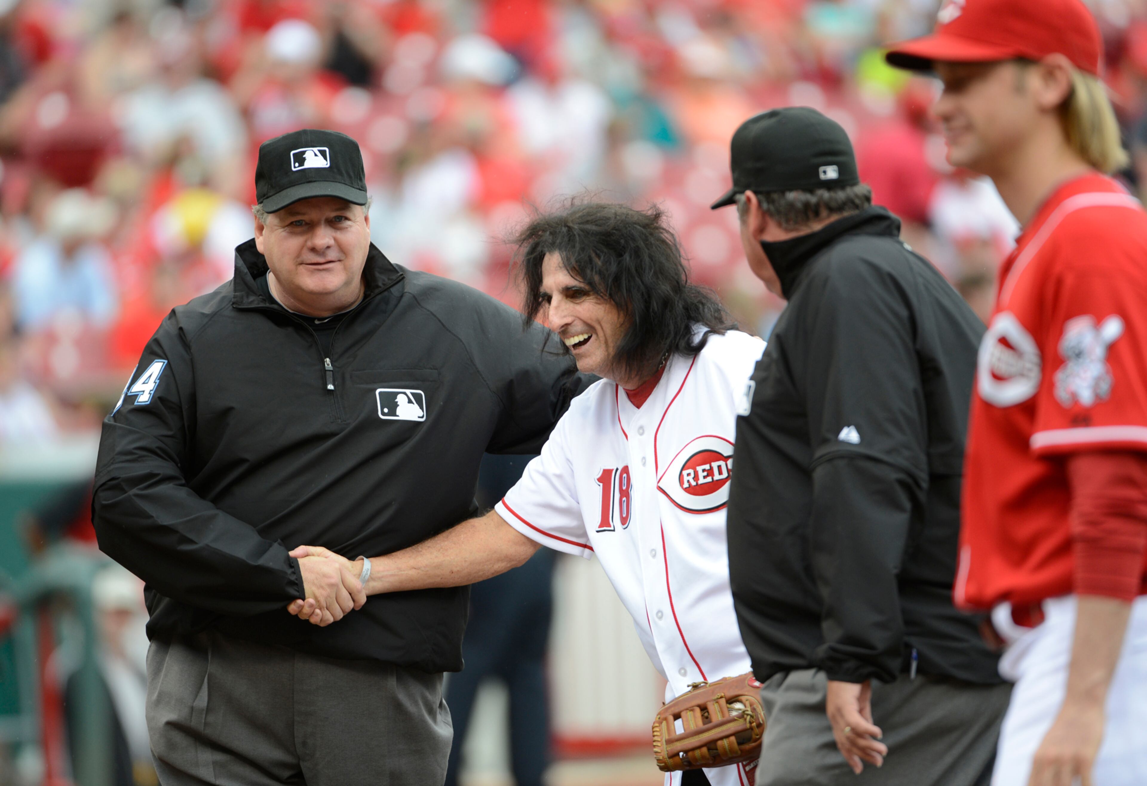 Rock and Roll Hall of Famer Alice Cooper shakes hands with National League Umpire Hunter Wendelstadt, left, after throwing out the ceremonial first pitch,Saturday, July 6, 2013, in a baseball game between the Cincinnati Reds and the Seattle Mariners at Great American Ball Park in Cincinnati. (AP Photo/Michael E. Keating)
