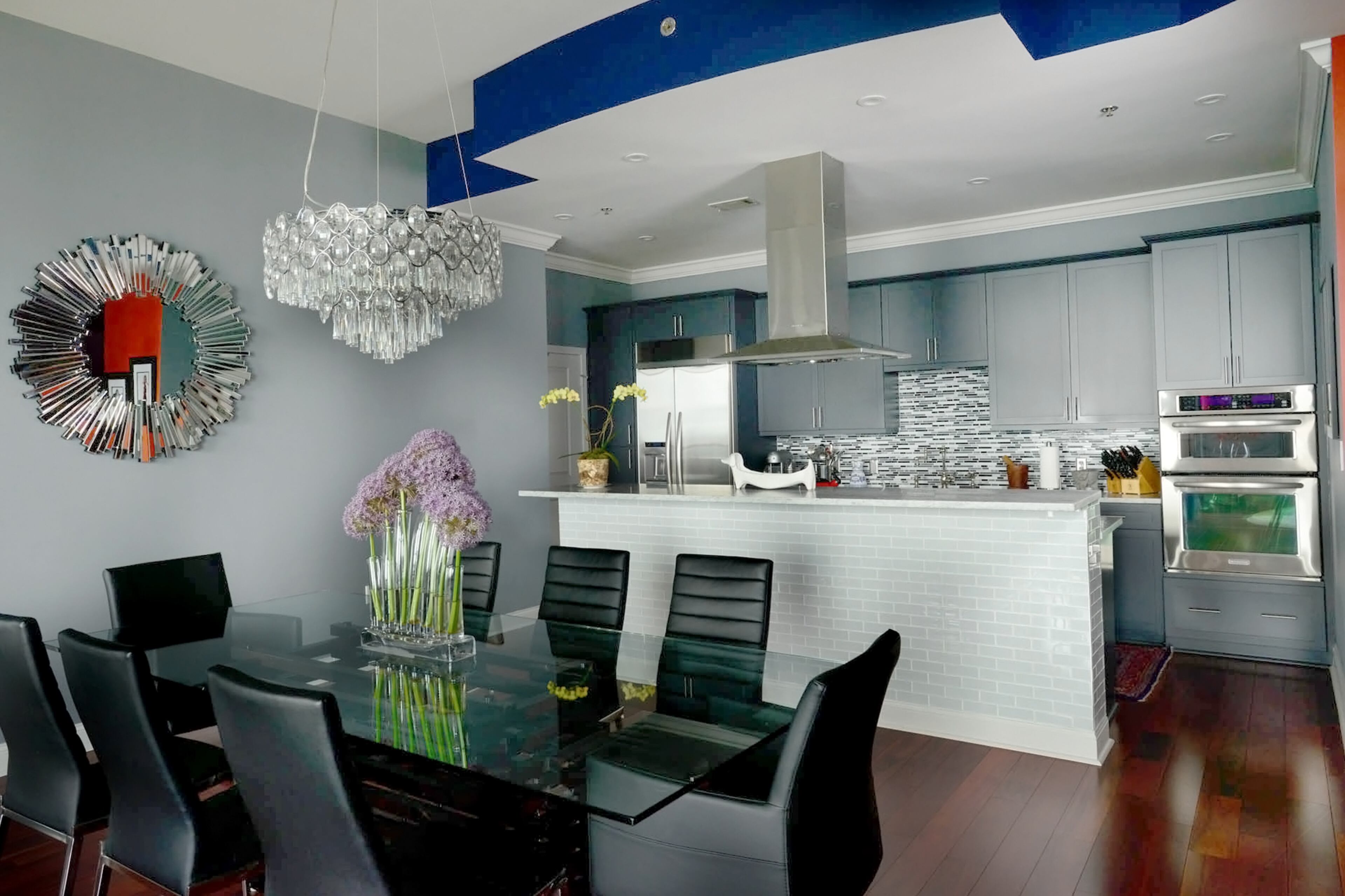 The condo' modern design is seen with the Carrara marble countertops from Miami Circle Marble & Fabrication, cabinets repainted gray and tile backsplash in the renovated kitchen. The homeowners also expanded the island, which opens up to the dining area with a crystal chandelier and modern furniture.