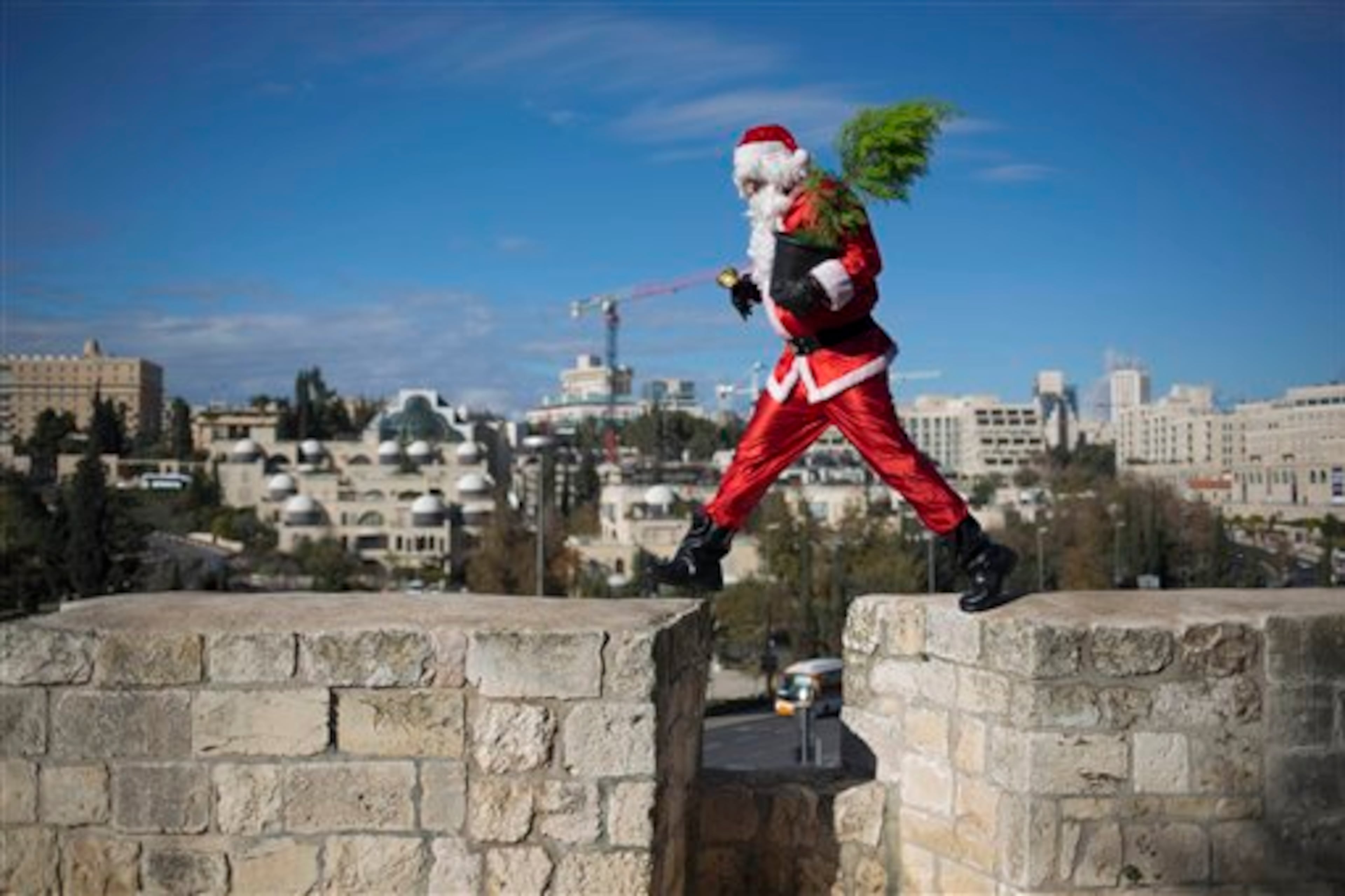 A man dressed as Santa Claus walks on the wall of the Old City in Jerusalem Monday, Dec. 22, 2014. (AP Photo/Dusan Vranic)