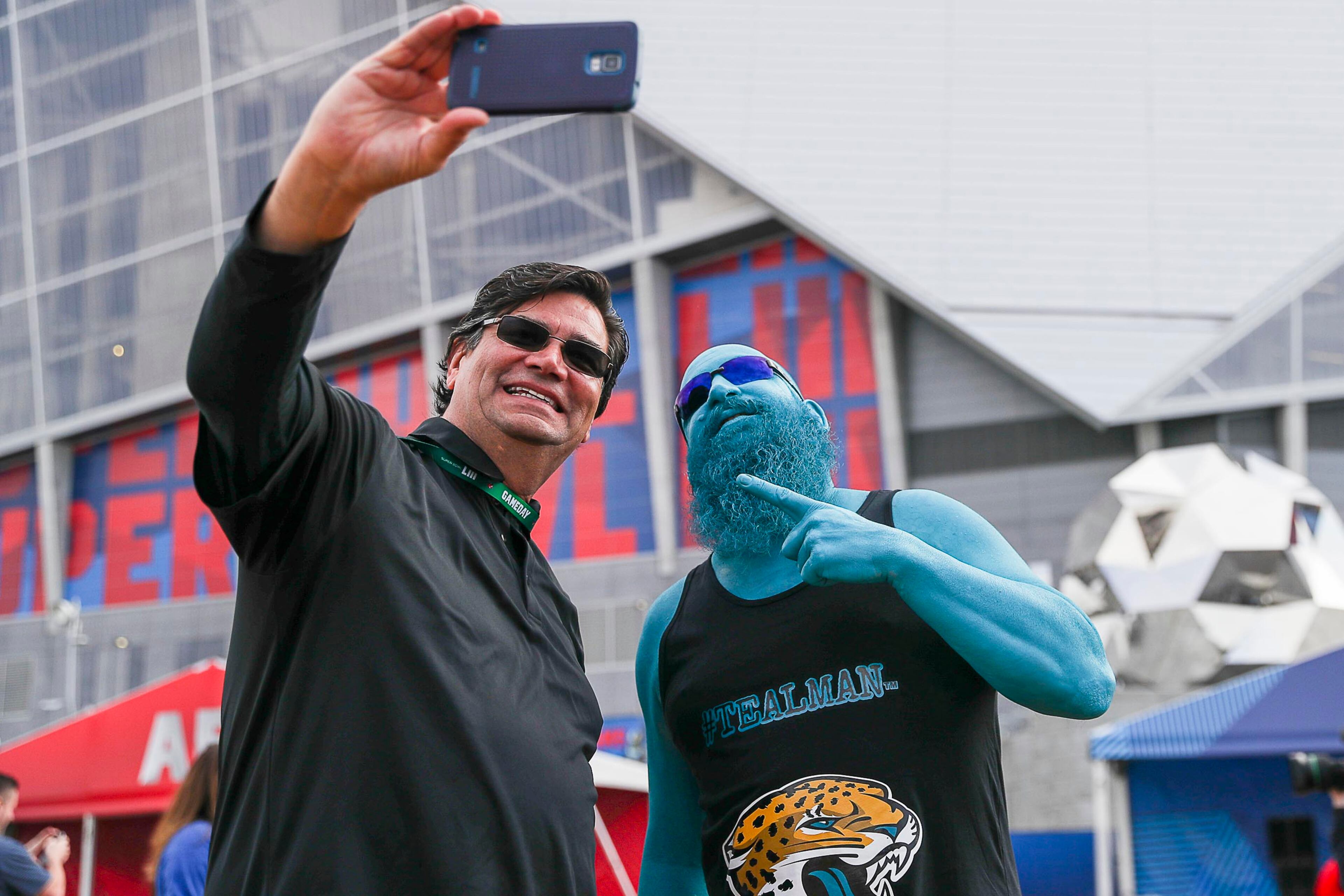 02/03/2019 -- Atlanta, Georgia -- Ryan Fettik (right), also known as Teal Man, takes a photo with a fan at the Home Depot Backyard Lot outside of Mercedes-Benz Stadium before the start of Super Bowl LIII on Sunday, February 3, 2019. (ALYSSA POINTER/ALYSSA.POINTER@AJC.COM)