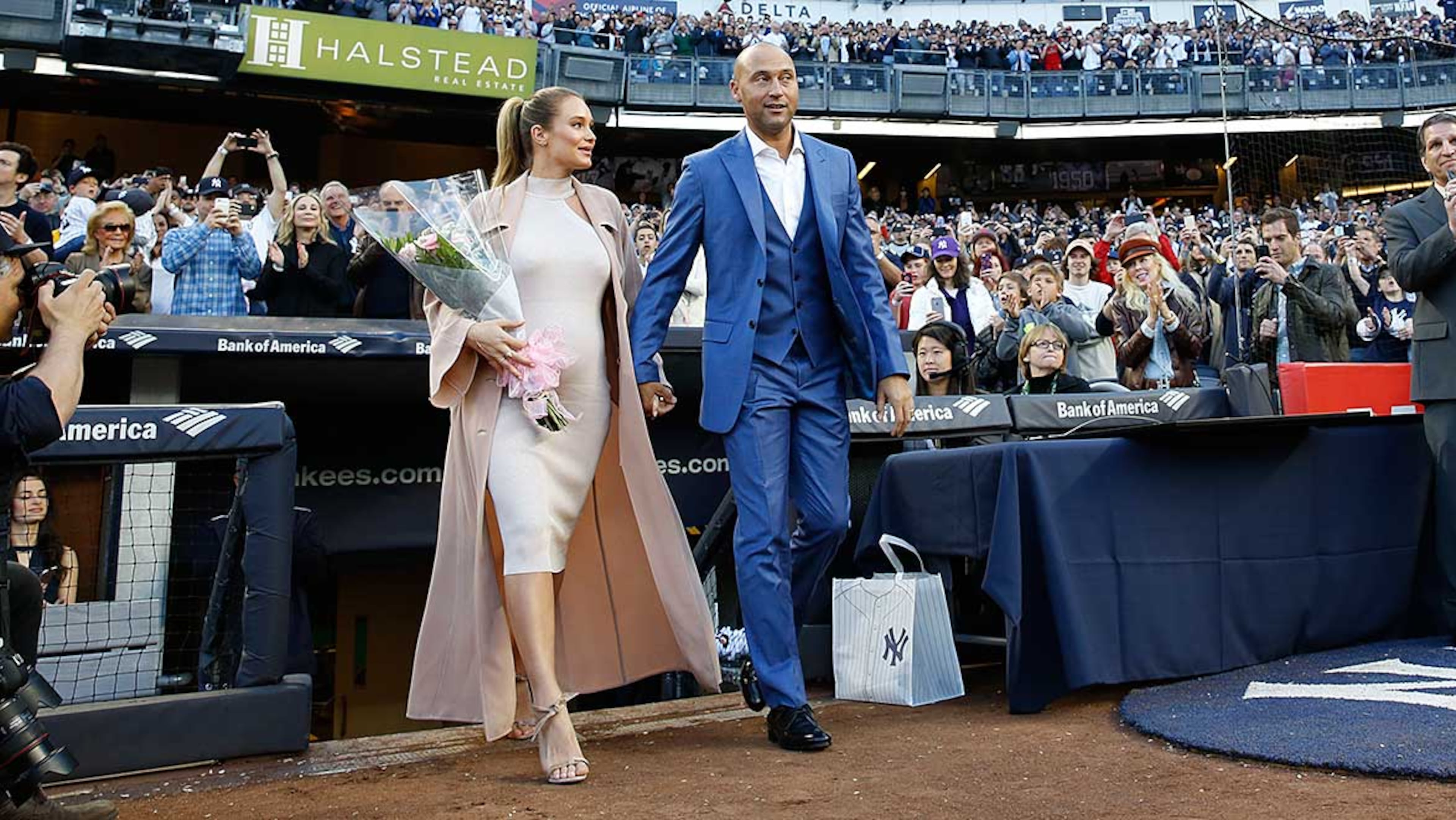 Derek Jeter and wife Hannah walk from the dugout to the field during a pregame ceremony retiring Jeter's number 2 in Monument Park at Yankee Stadium Sunday.