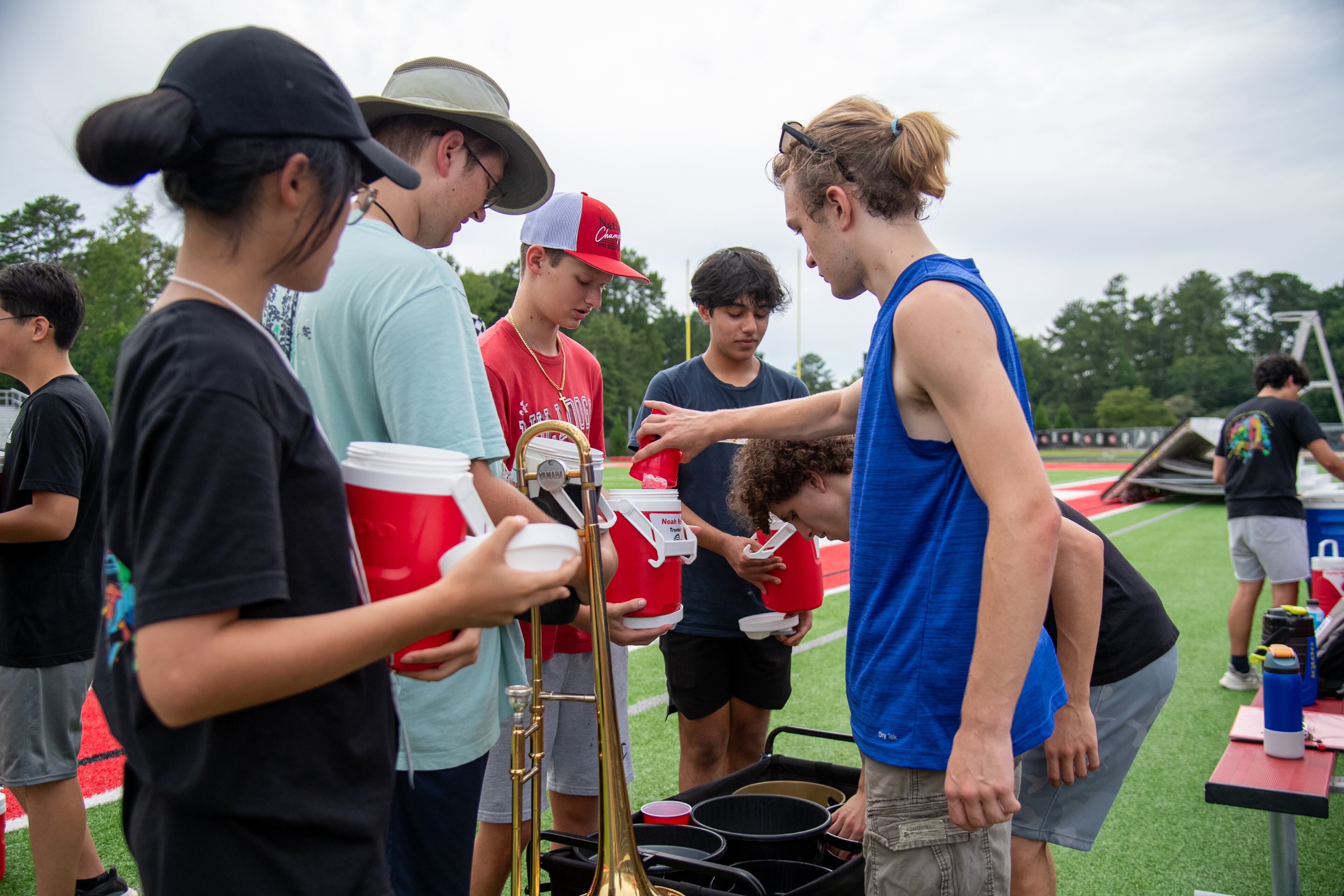 The drum majors serve ice to their band mates Wednesday, July 26, 2023, to help keep them on their toes during practice at North Gwinnett HS. (Jamie Spaar for the Atlanta Journal-Constitution)