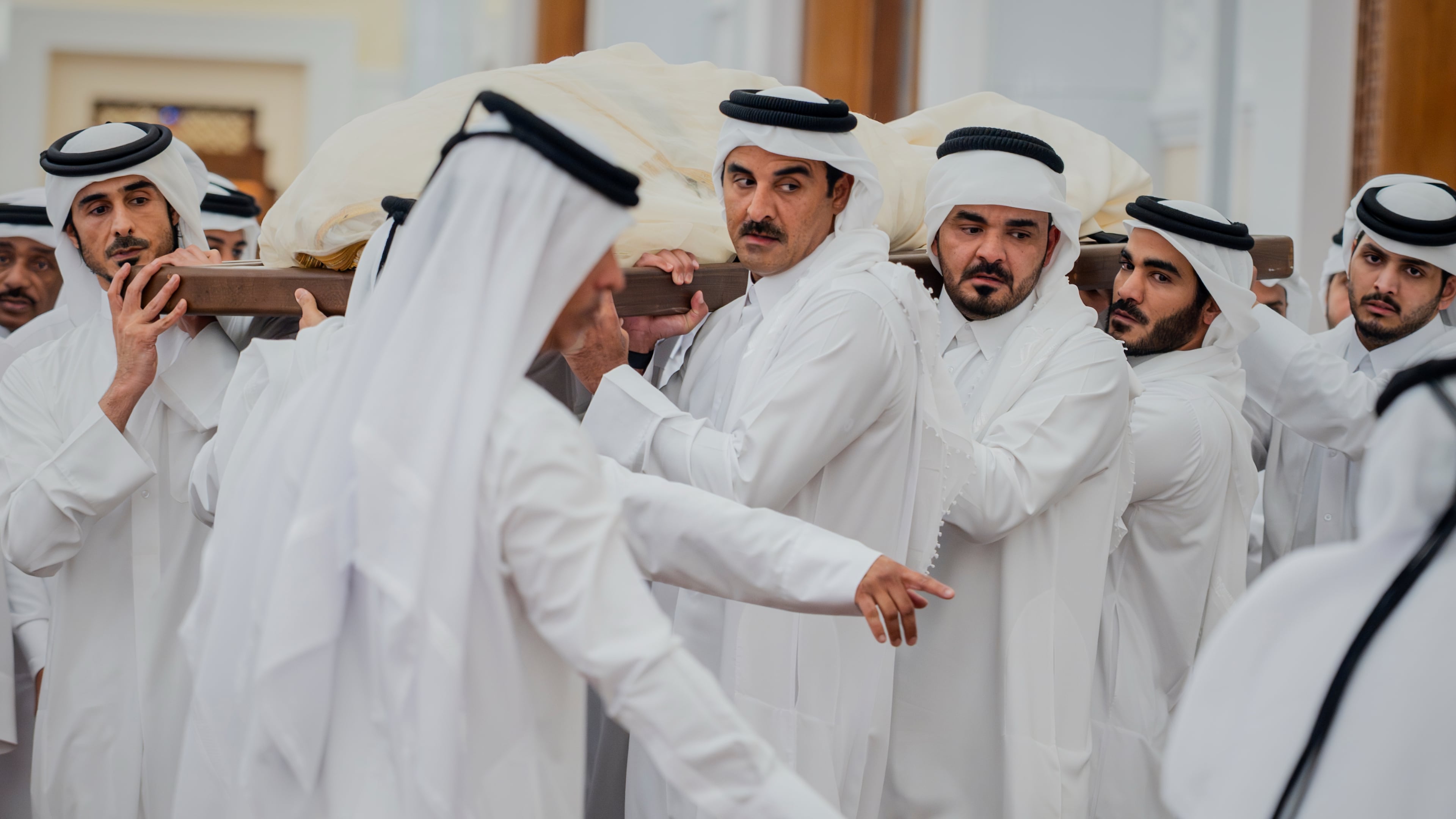 In this picture released by the Qatar Amiri Diwan media office, Qatari Emir Sheikh Tamim bin Hamad Al Thani helps carry the bier bearing the body of his father, Qatar's former ruler Sheikh Hamad bin Khalifa Al Thani, with other mourners for a funeral prayer at the Mohammed bin Abdulwahab Mosque in Doha, Qatar, Sunday, July 12, 2026. (Qatar Amiri Diwan via AP)