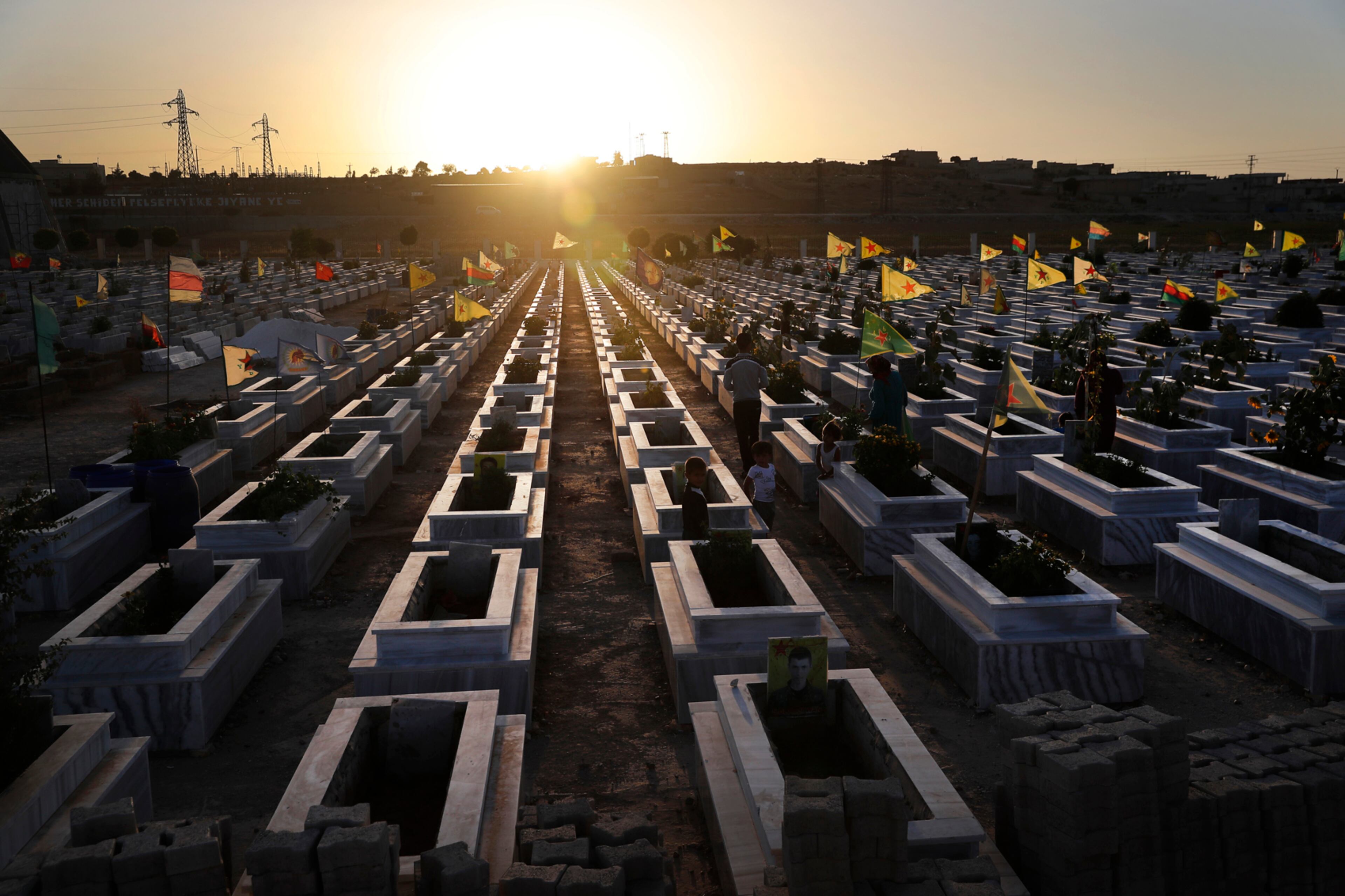 Kurdish citizens visit the graves of their relatives who were killed while fighting against Islamic State militants in Raqqa and other places, at a cemetery in Kobani, Syria, Friday, July 28, 2017. Islamic State militants have carried out a deadly attack on U.S.-backed forces in Syria, killing and wounding many fighters and civilians, Syrian monitors and an IS-linked media outlet said Friday. (AP Photo/Hussein Malla)