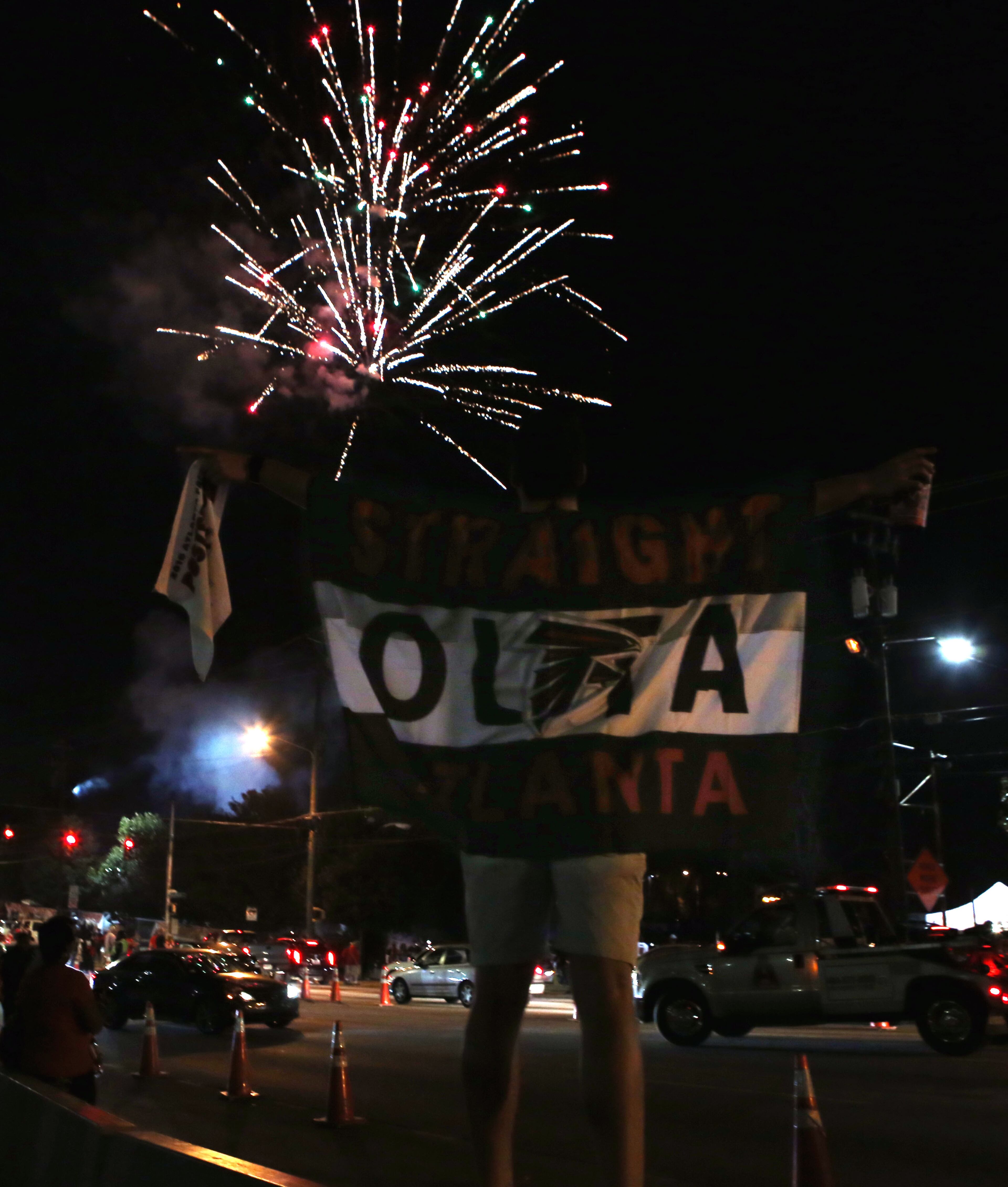 January 14, 2017, Atlanta - A fan clambers onto the concrete barrier to fly his "STRAIGHT OUTTA ATLANTA" flag to all who can see in the show of fireworks being launched just a few blocks away in Atlanta, Georgia, on Saturday, January 14, 2017. (HENRY TAYLOR / HENRY.TAYLOR@AJC.COM)