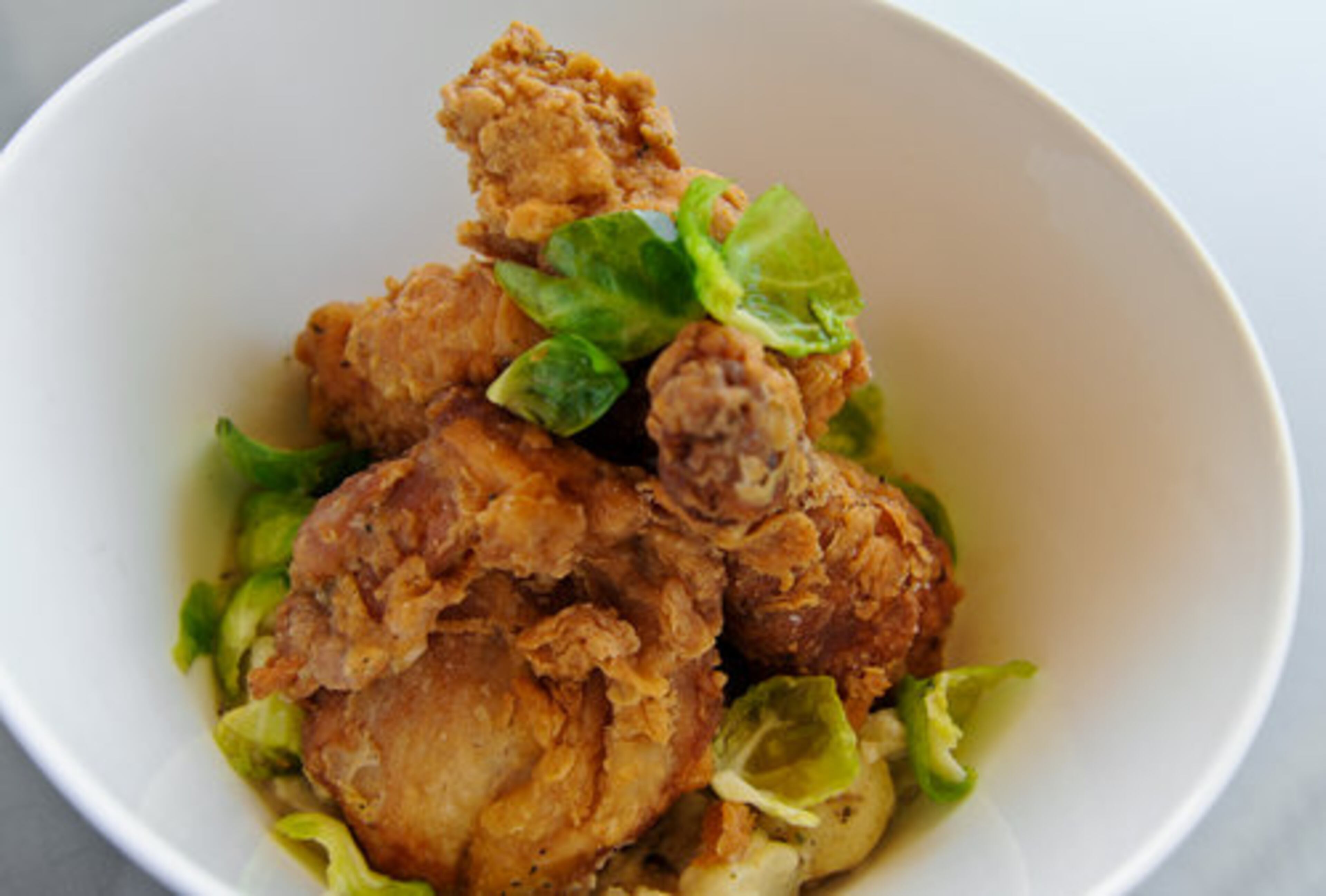 Buttermilk fried chicken with creamed potatoes, Brussels sprouts leaves and cracked pepper gravy at Southern Art and Bourbon Bar in Buckhead. After a 10-year stint as Oprah Winfrey's personal chef, Art Smith opened restaurants in Chicag, Washington, D.C. and California. His newest spot features new takes on Southern classics like a honey-lacquered half-duck with duck fat-basted root vegetables.