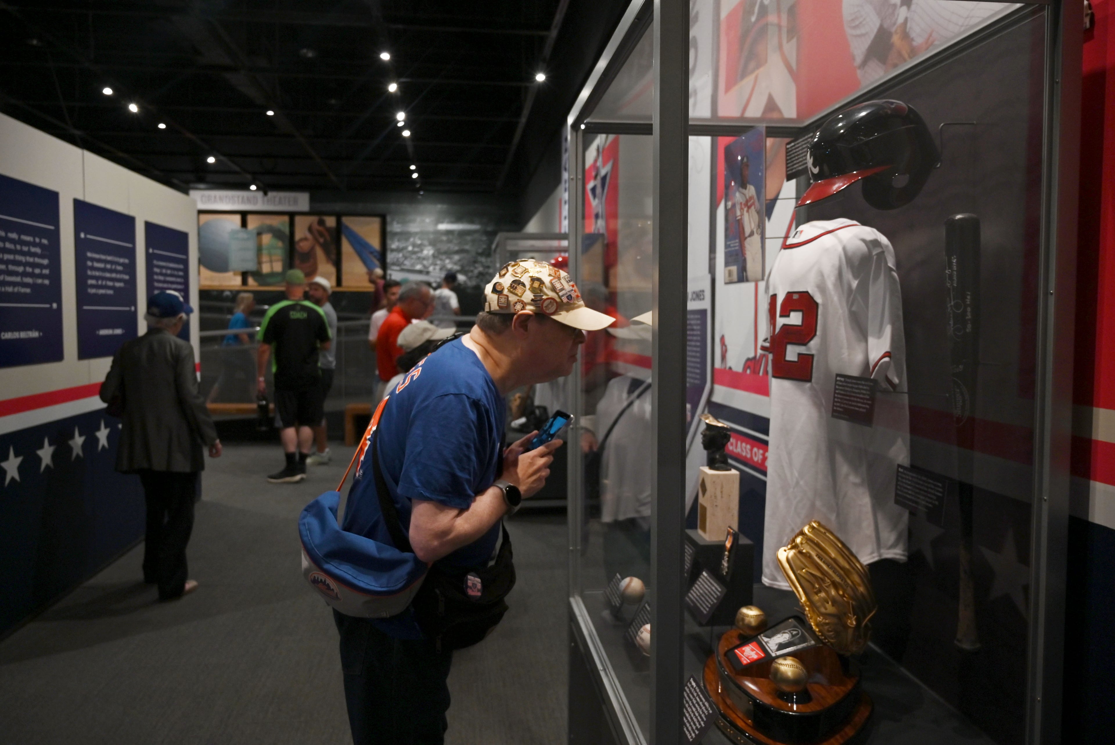 Andrew Rosenthal of Queens, New York, checks out displays featuring former Atlanta Braves center fielder Andruw Jones at the National Baseball Hall of Fame and Museum on Friday, July 24, 2026, in Cooperstown, N.Y. Andruw Jones will be inducted into the National Baseball Hall of Fame on Sunday as part of the Class of 2026, alongside Carlos Beltrán and Jeff Kent. He is recognized as one of the greatest center fielders in baseball history. Jones will become the 12th player with ties to the Atlanta Braves to be inducted into the Hall of Fame. (Hyosub Shin/AJC)