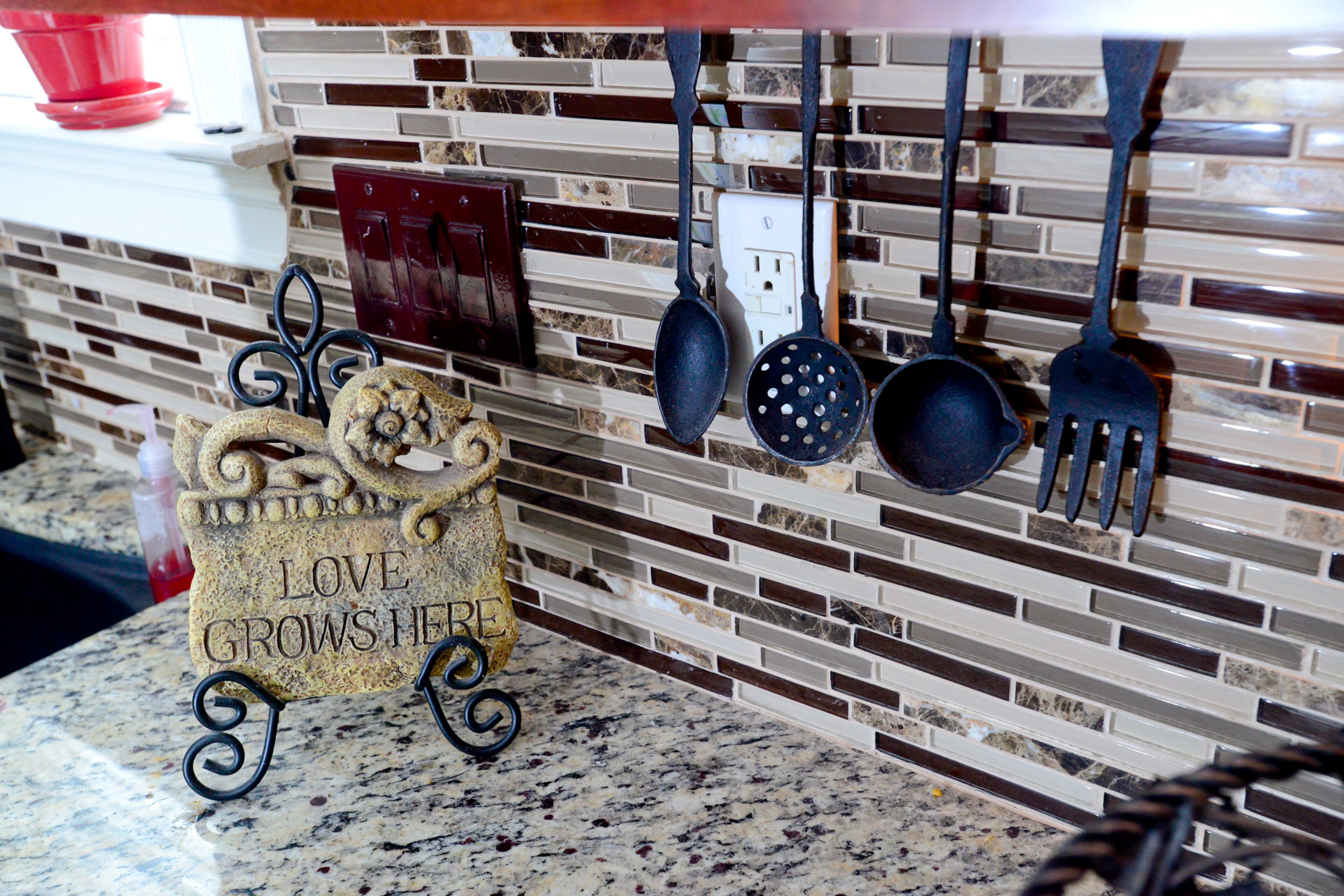 Homeowner Frances Pace picked out the brown and beige glass tile to soften the granite in the kitchen. The hanging utensils are within easy reach, but also decorative.