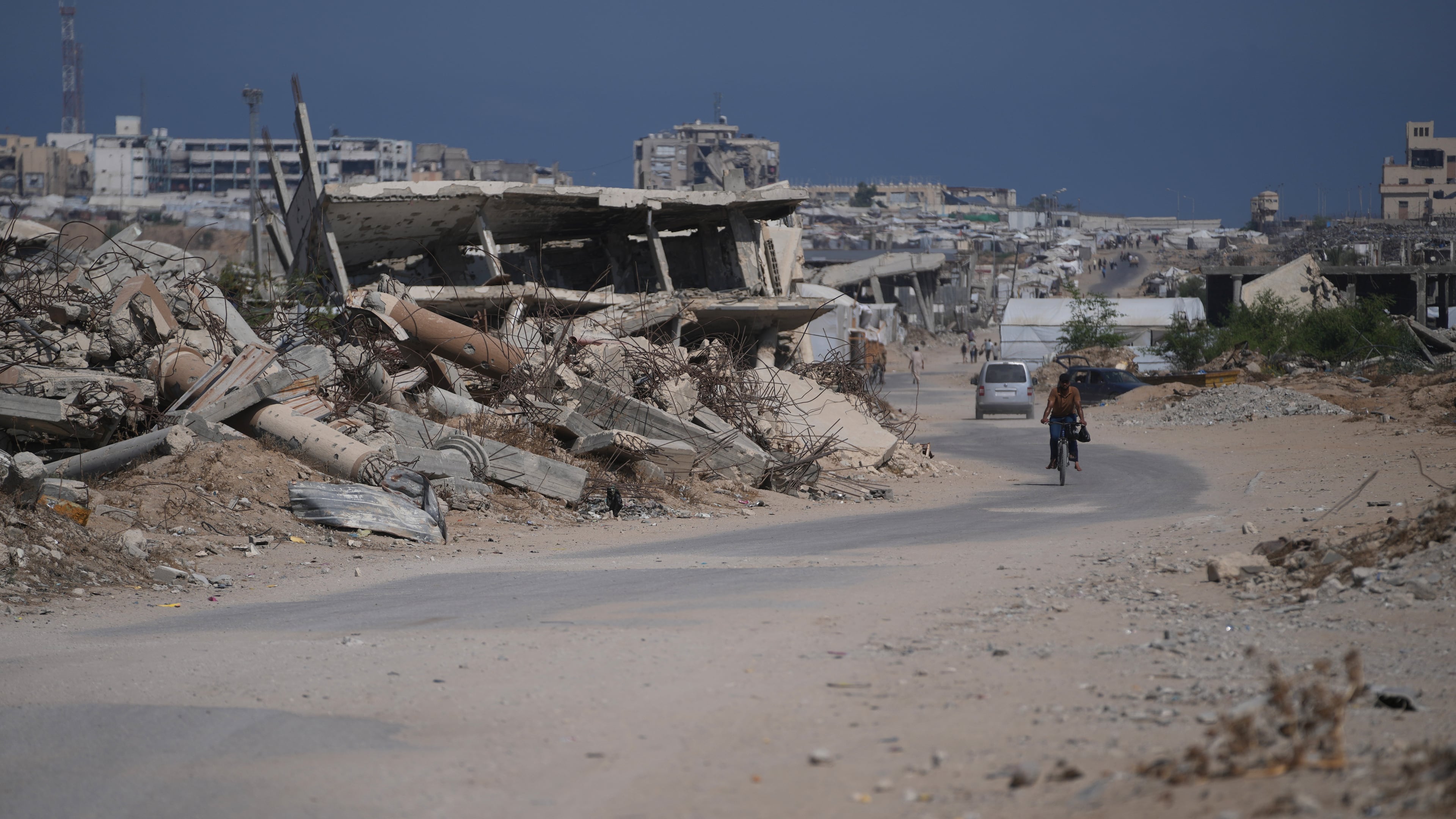 A Palestinian man rides his bicycle by the rubble of buildings that were destroyed during the Israel Hamas war, in Khan Younis, southern Gaza Strip, Friday, July 31, 2026. (AP Photo/Abdel Kareem Hana)