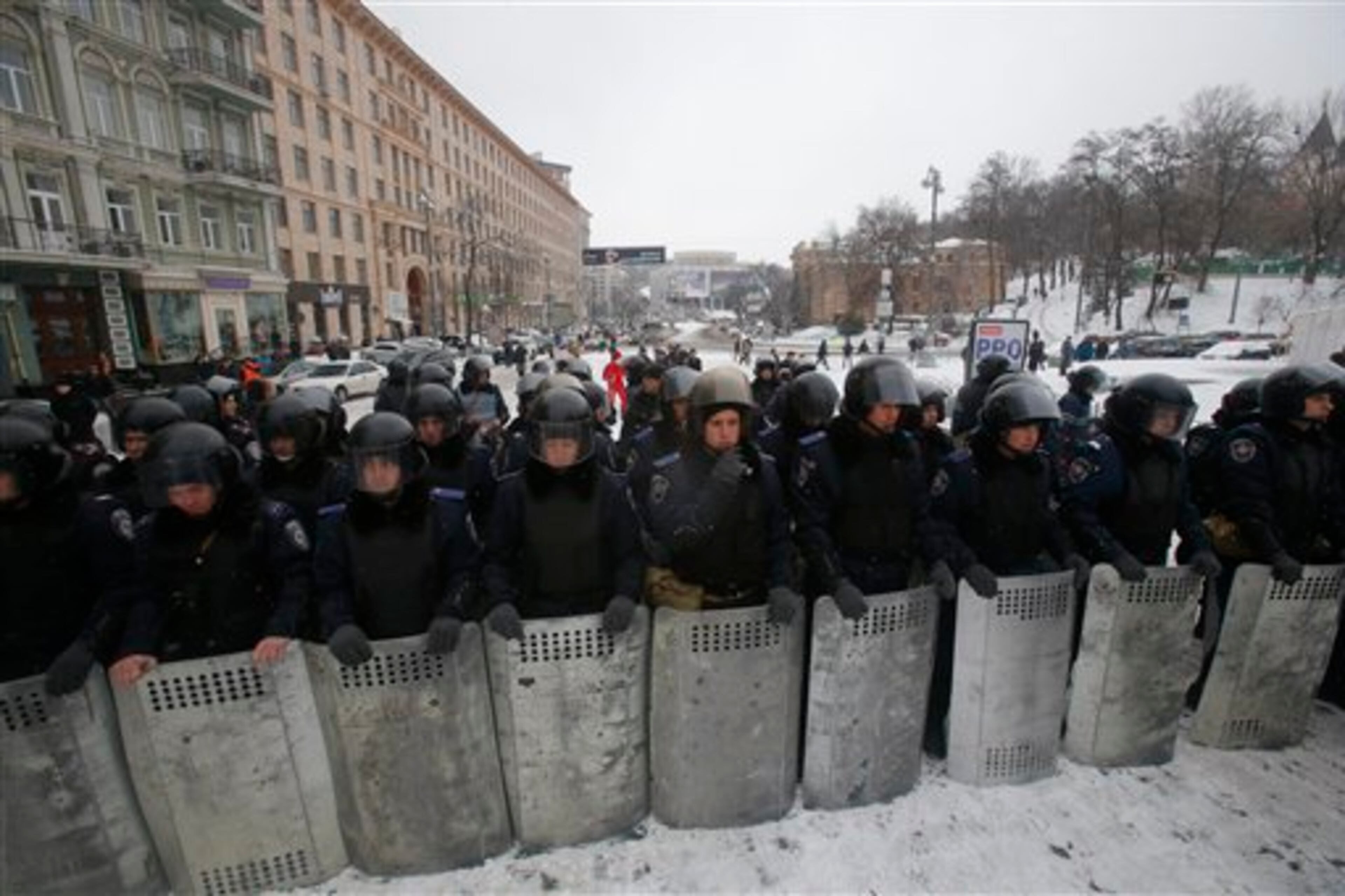 Ukrainian riot police block the road next to Pro-European Union activists gathered on the Independence Square in Kiev, Ukraine, Monday, Dec. 9, 2013. The policemen, wearing helmets and holding shields, formed a chain across Kiev�s main street outside the city building. Organizers called on protesters to vacate the city hall and the other building which the opposition had used as its headquarters. (AP Photo/Sergei Grits)