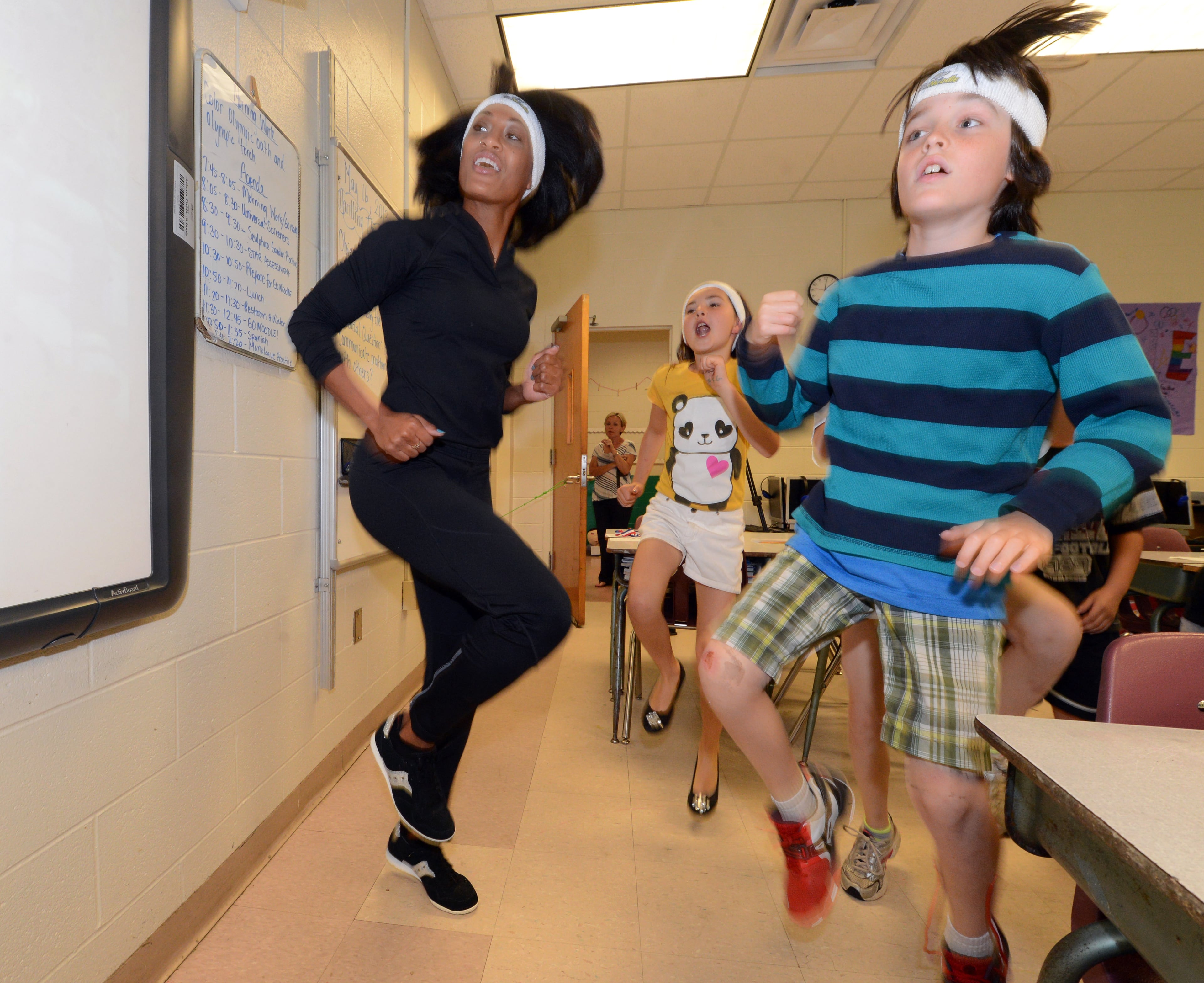 Olympic hurdler Queen Harrison practices the l100m hurdles with third graders Keely Baker and Colton Kettering at Mary Lin Elementary School.