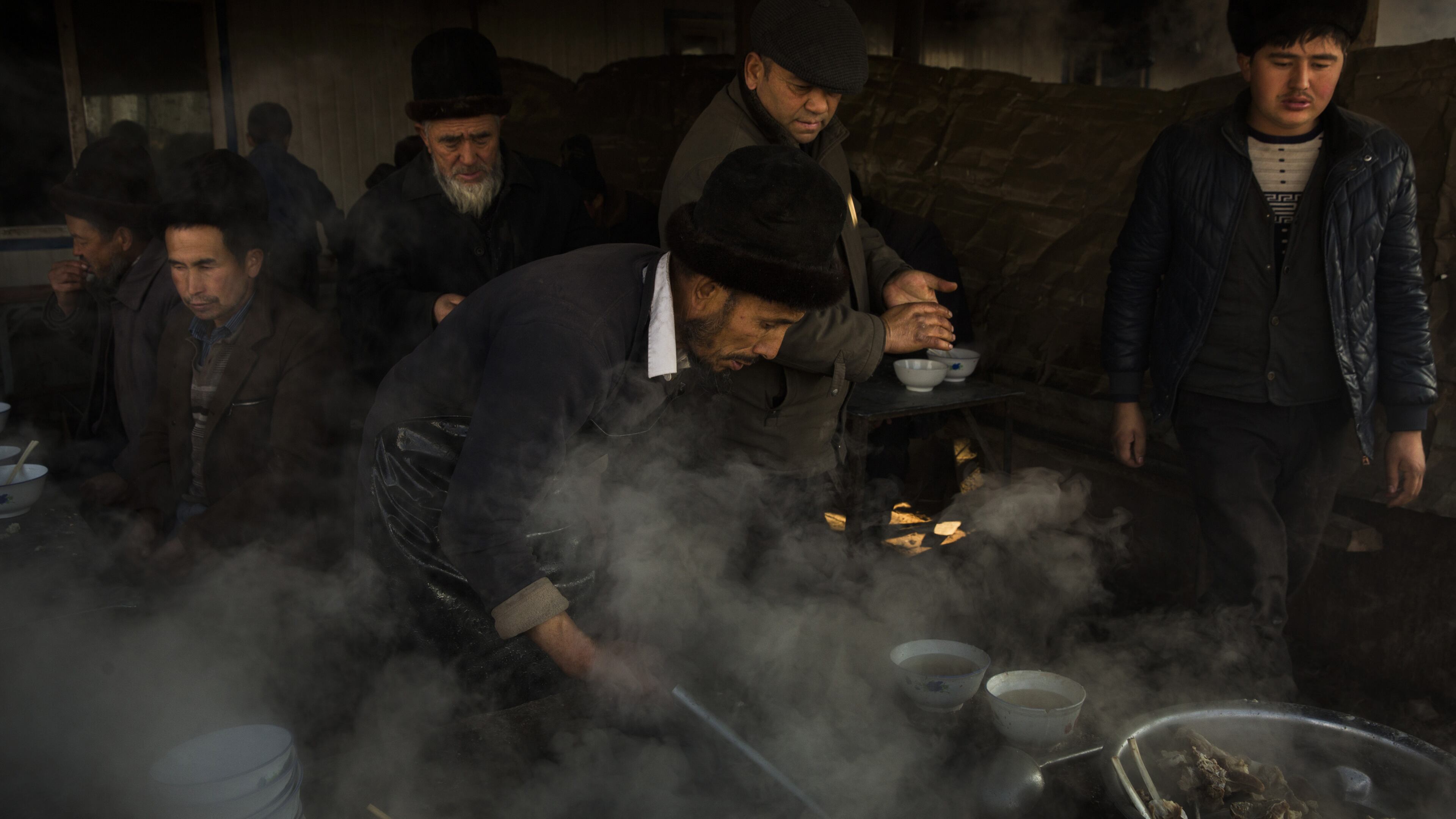 Uighur men prepare food at a livestock market in Kashgar, in China’s far western province of Xinjiang. (Adam Dean/The New York Times)