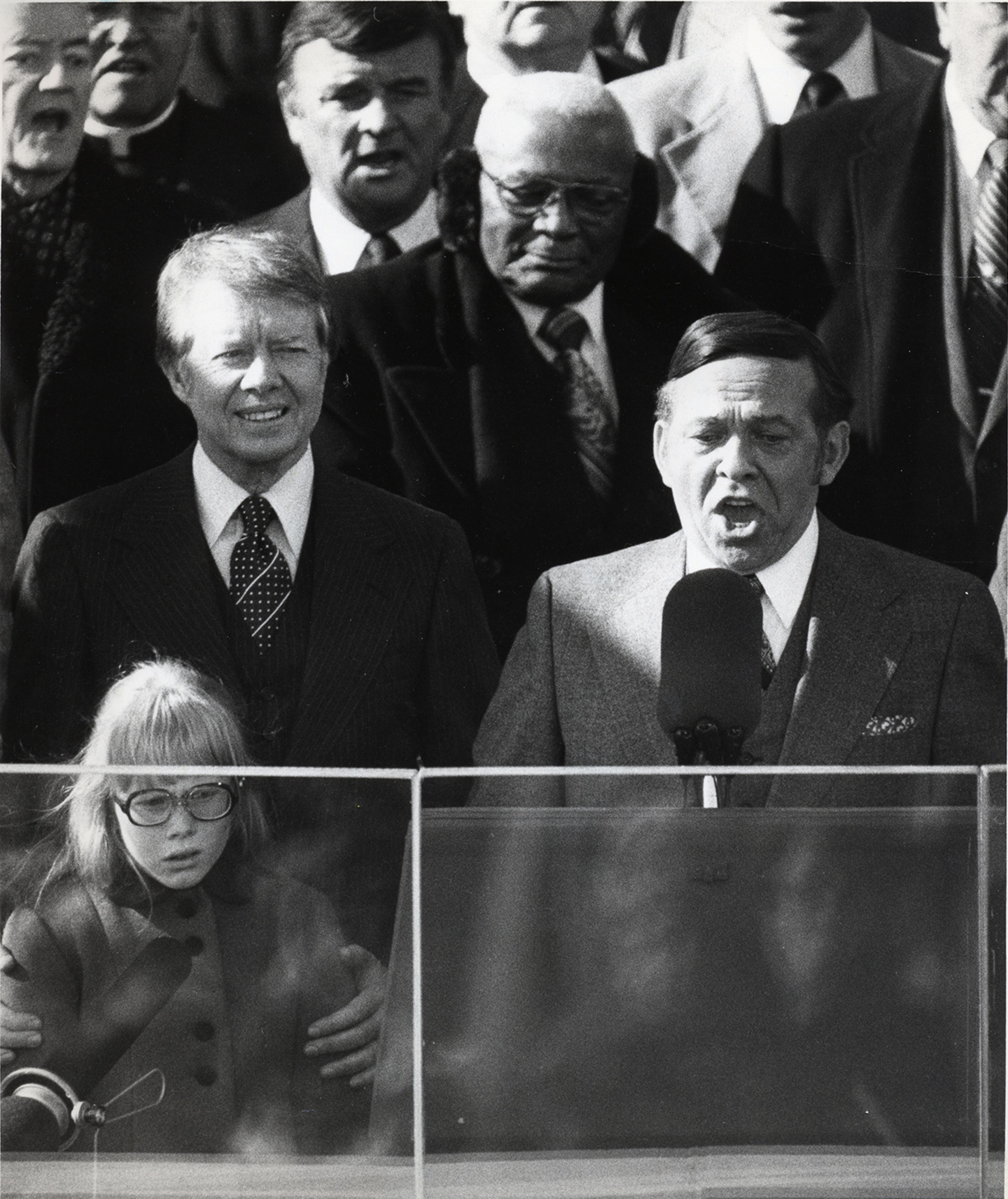 Rep. Carl Albert speaks alongside Jimmy and Amy Carter at the 1977 presidential inauguration. M. L. King Sr. stands over their shoulders.