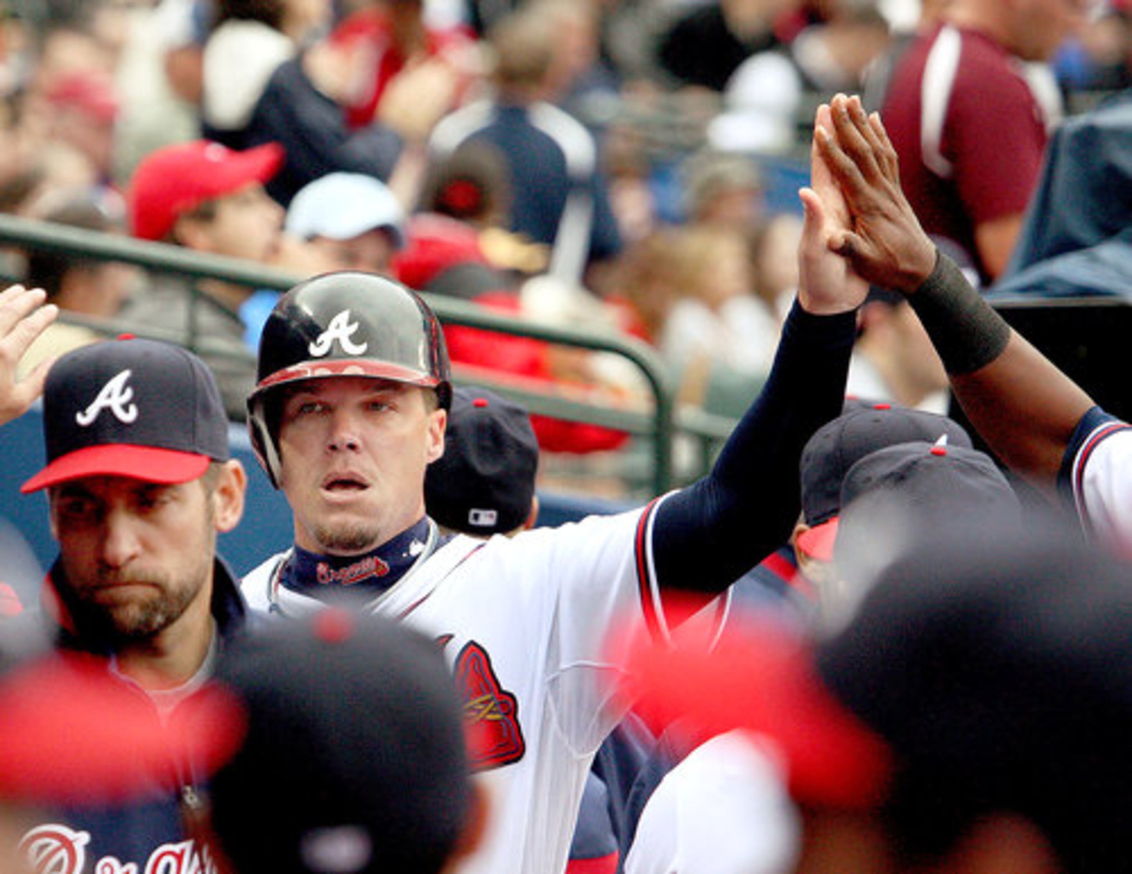 Chipper Jones gives a high five to another player after scoring during the third inning.