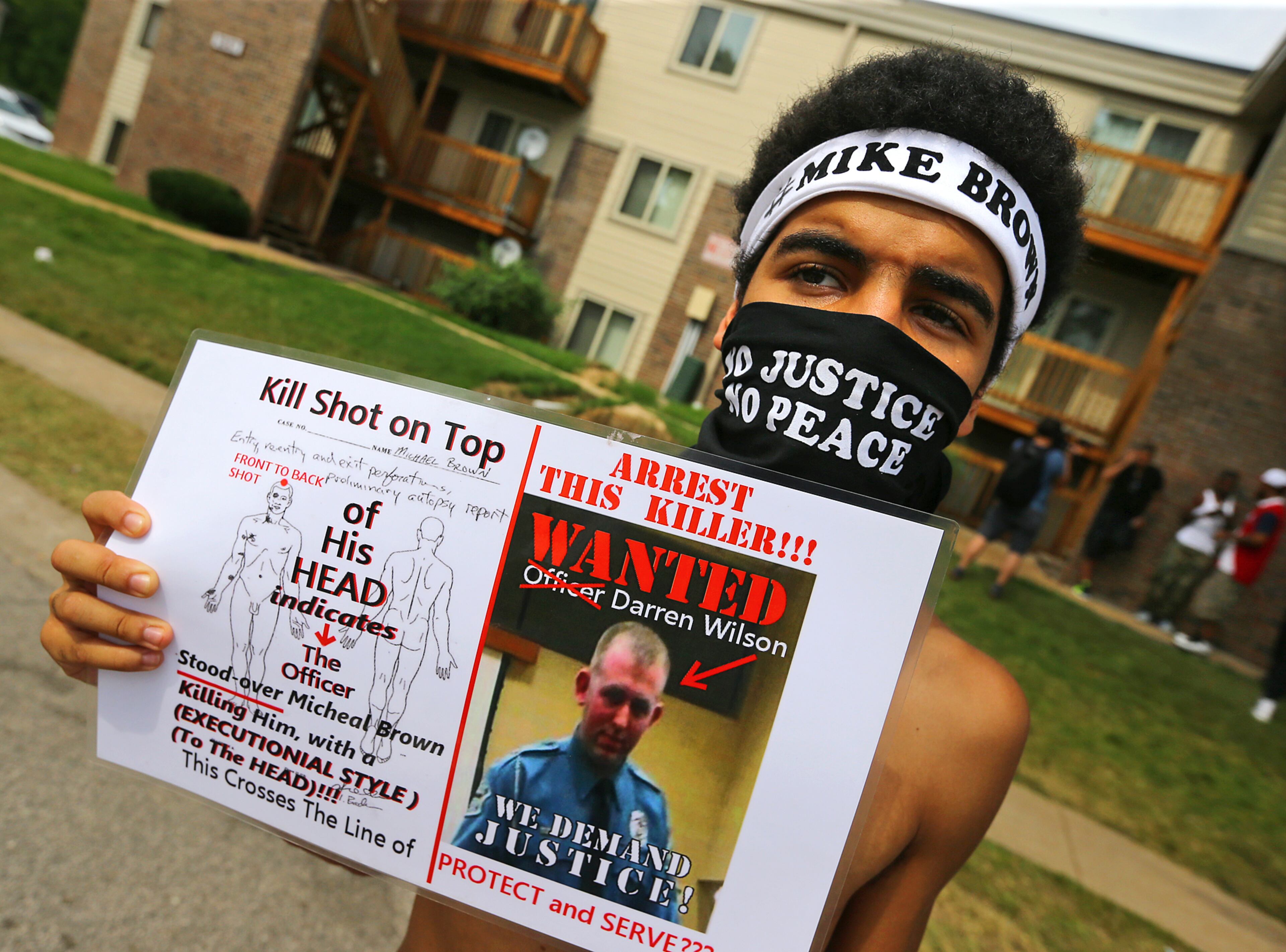 Quentin Baker, Crystal City, MO, holds a sign near the shrine to Michael Brown in the Canfield Apartments on Wednesday, Aug. 20, 2014, in Ferguson. CURTIS COMPTON / CCOMPTON@AJC.COM