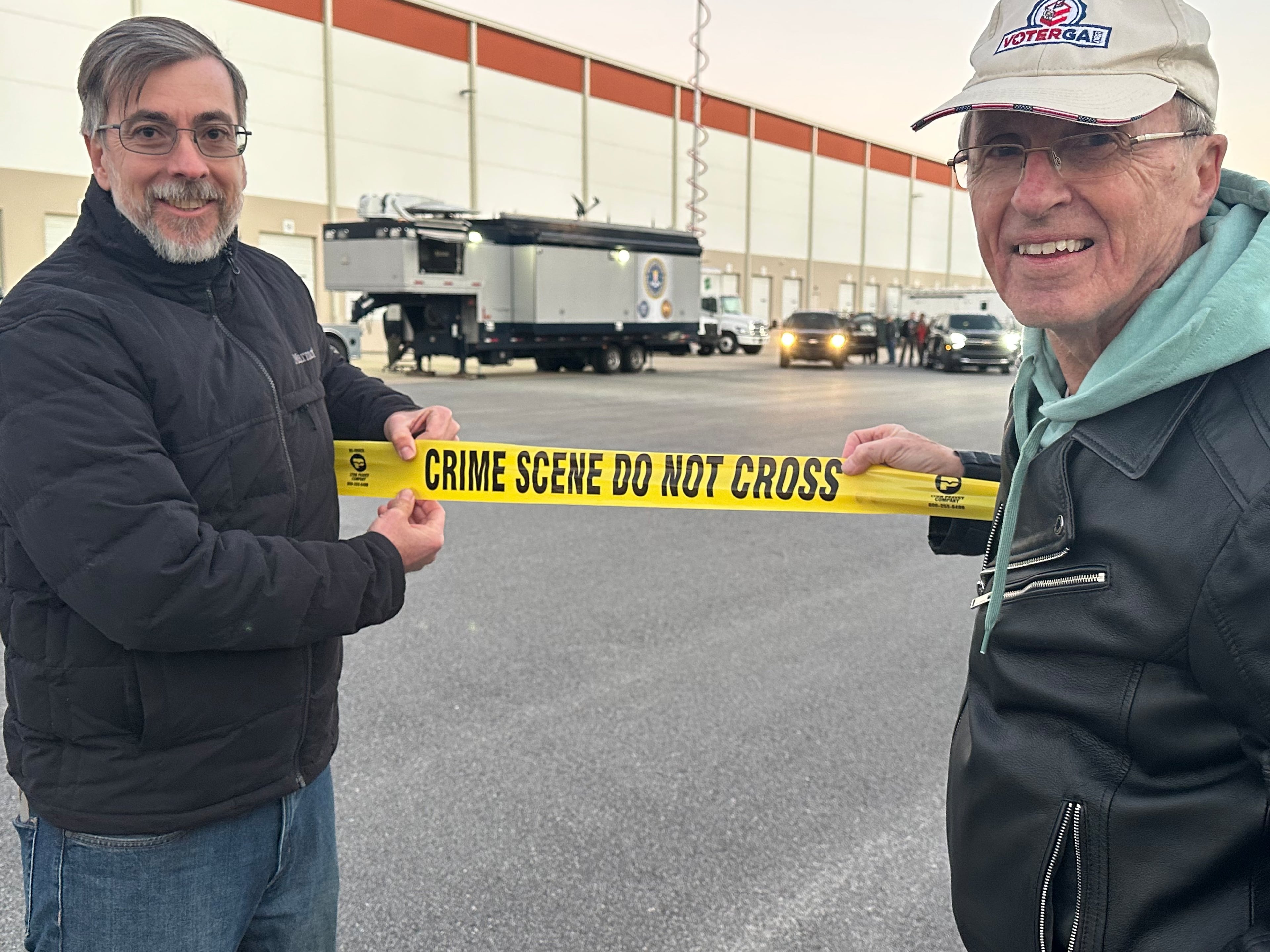 Election integrity activists Jason Frazier and Garland Favorito pose at the scene of the Jan. 28 FBI raid on the Fulton County election hub. (Social media post)