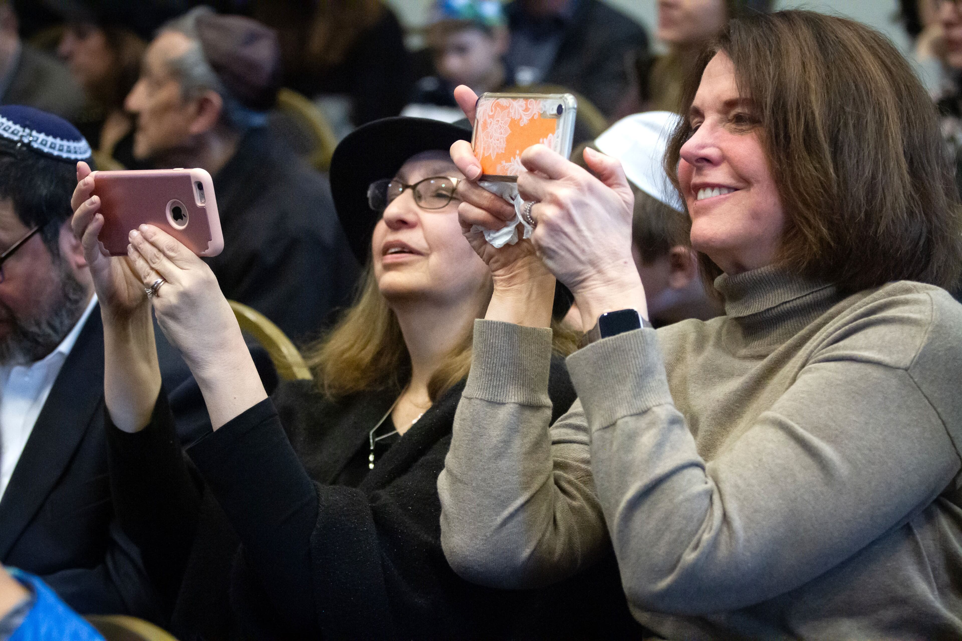 Eileen Botvinick (L) and Wendy Asher take photographs of the historic Torah scroll during a celebration of the Torah's completion at the Chabad of Cobb Sunday, March 8, 2020. STEVE SCHAEFER / SPECIAL TO THE AJC