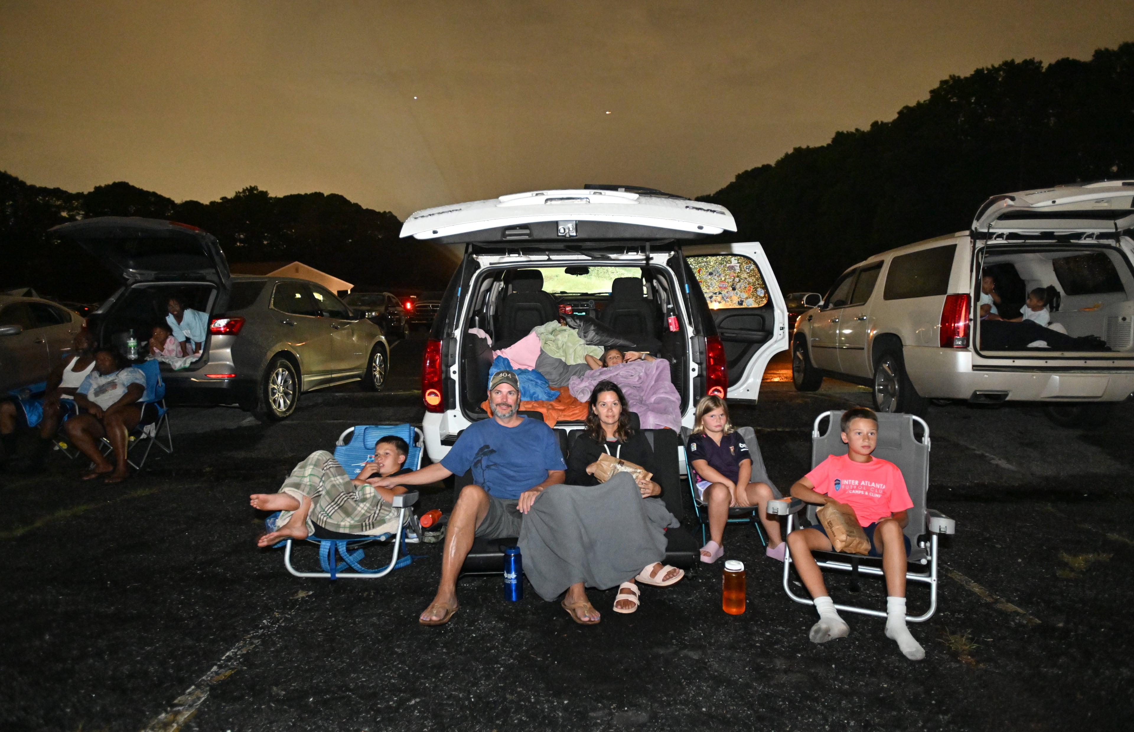 Steve Ware and his girlfriend Samantha Wade with their children (from left) Charlie Ware, Eva Strain (above), Eliza Jane Ware and Henry Strain watch "Lilo & Stitch" at Starlight Drive-In Theatre, Friday, June 13, 2025, in Atlanta. (Hyosub Shin/AJC)