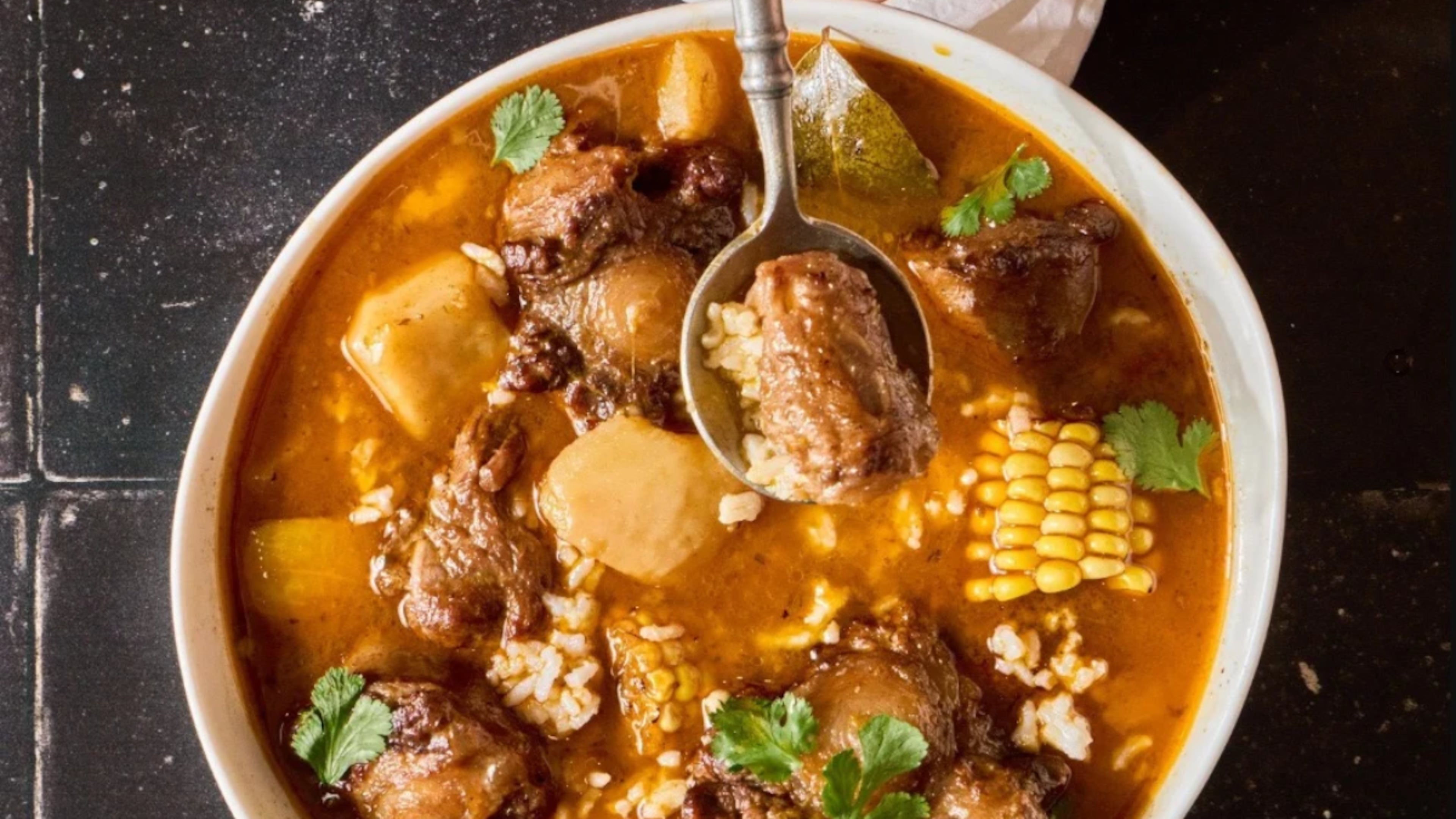A steaming bowl of sancocho is a hearty way to celebrate Hispanic Heritage Month. Monti Carlo's recipe from her debut cookbook, Spanglish, is loaded with oxtails, corn, green plantain and root vegetables. (Courtesy of Rafael N. Ruiz Mederos)