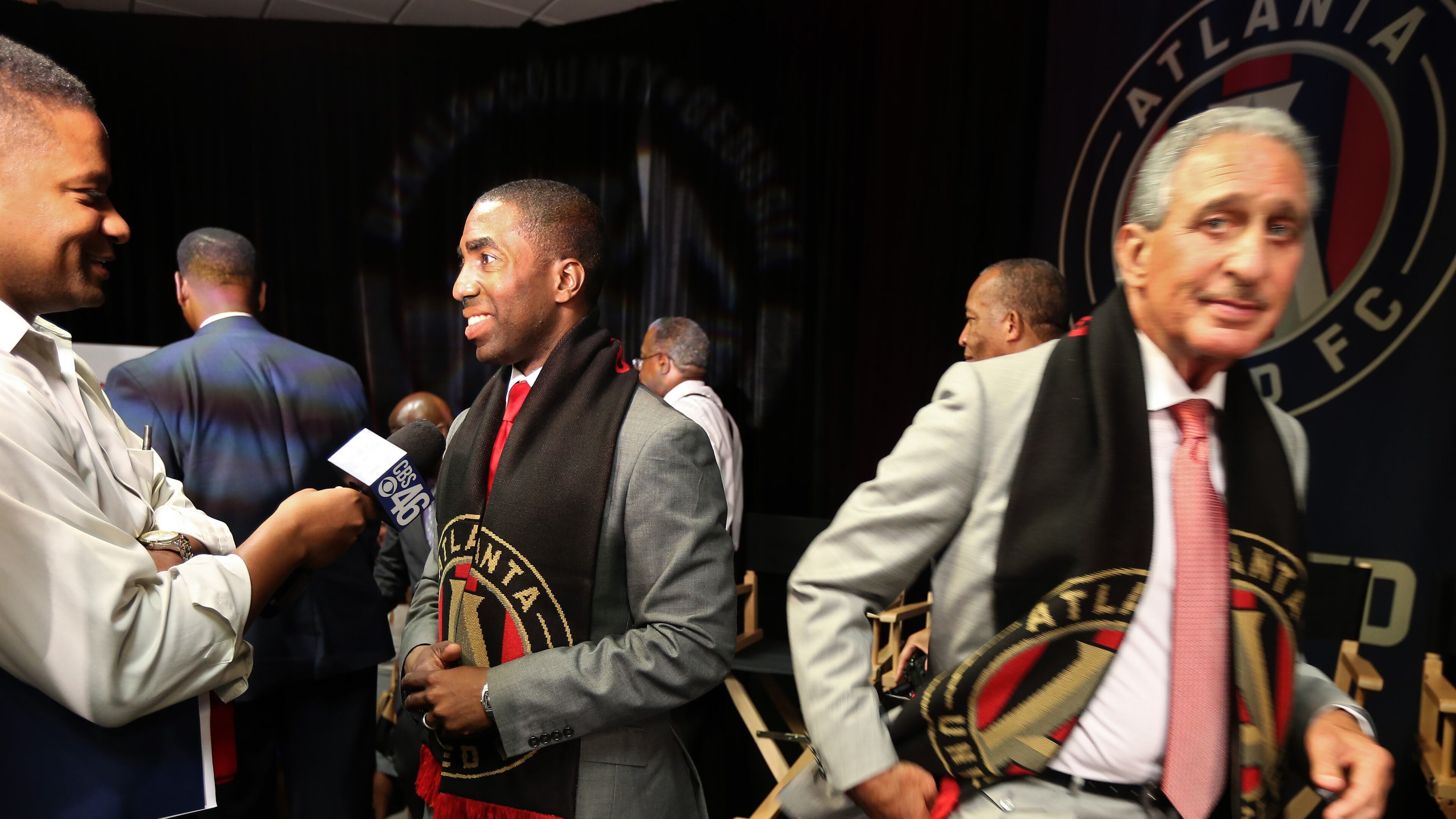 DeKalb County Interim CEO Lee May, left, answers a reporter’s questions as Arthur Blank slips past following a Tuesday afternoon announcement that Atlanta United FC would locate their headquarters and practice facility in DeKalb Couny. Ben Gray, bgray@ajc.com