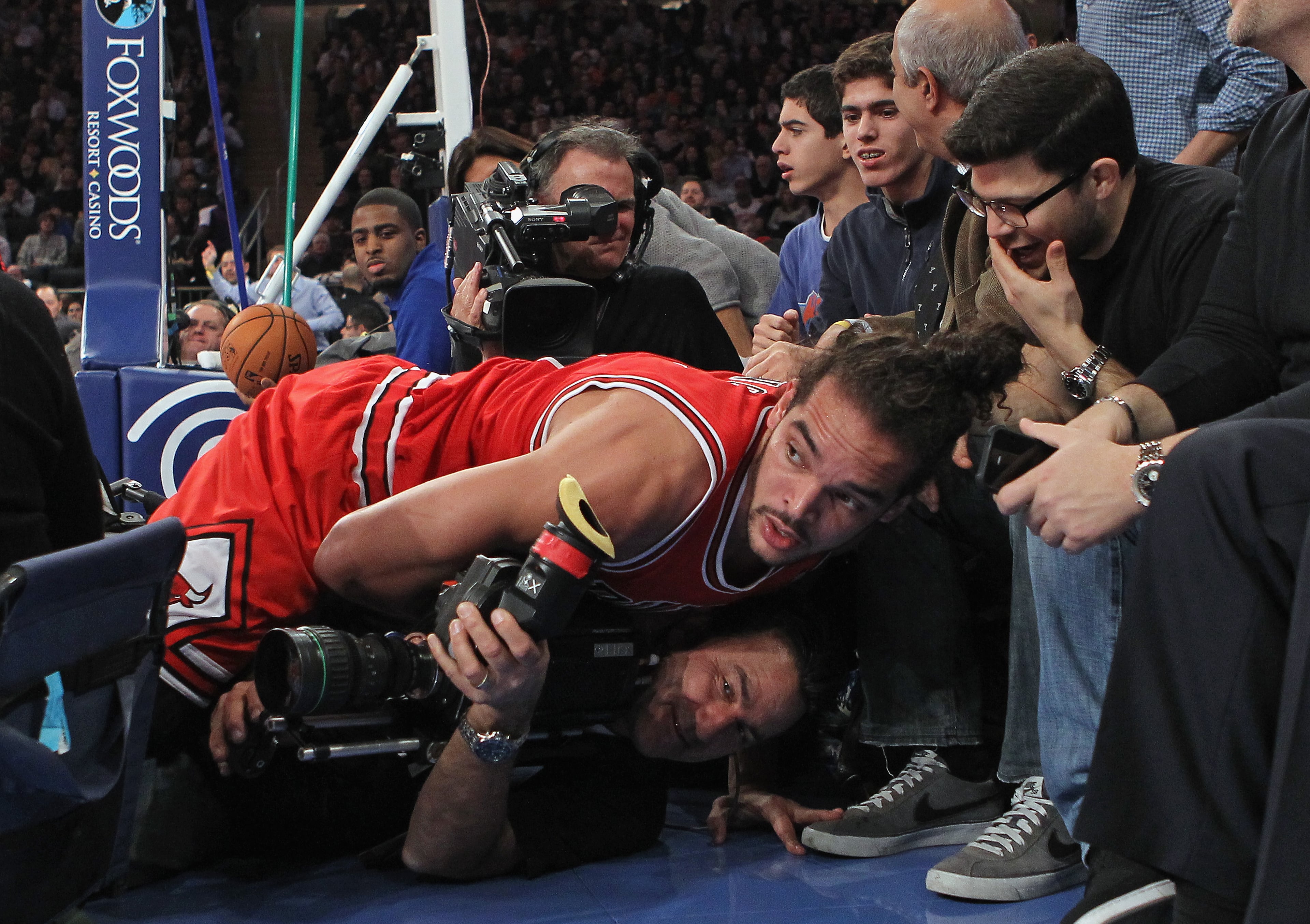 Joakim Noah #13 of the Chicago Bulls lands on a TV camerman as actor Jerry Ferrera of Entourage (R) looks on during the second quarter against the New York Knicks at Madison Square Garden on December 21, 2012 in New York City. NOTE TO USER: User expressly acknowledges and agrees that, by downloading and/or using this photograph, user is consenting to the terms and conditions of the Getty Images License Agreement. The Bulls defeated the Knicks 110-106. (Photo by Bruce Bennett/Getty Images)