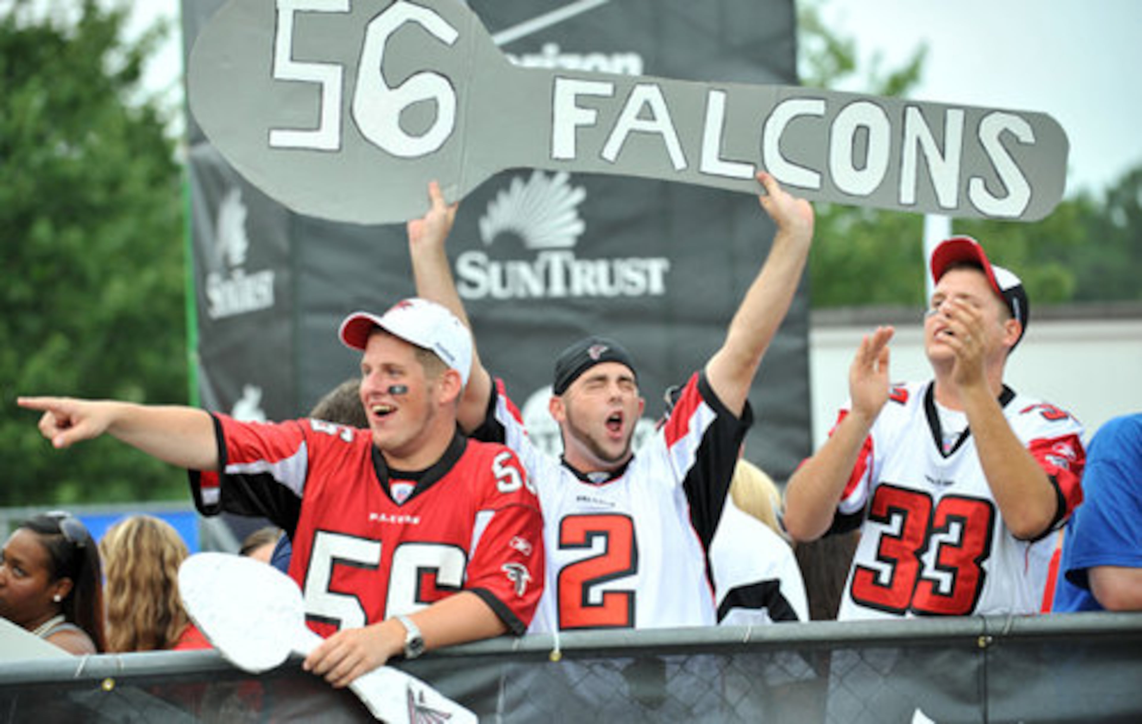 Atlanta Falcons fans, from left, Covey White, Patrick Gould and Stephen Rush cheer as Falcons players take the field during the Friday Night Lights at North Gwinnett High School in Suwanee.
