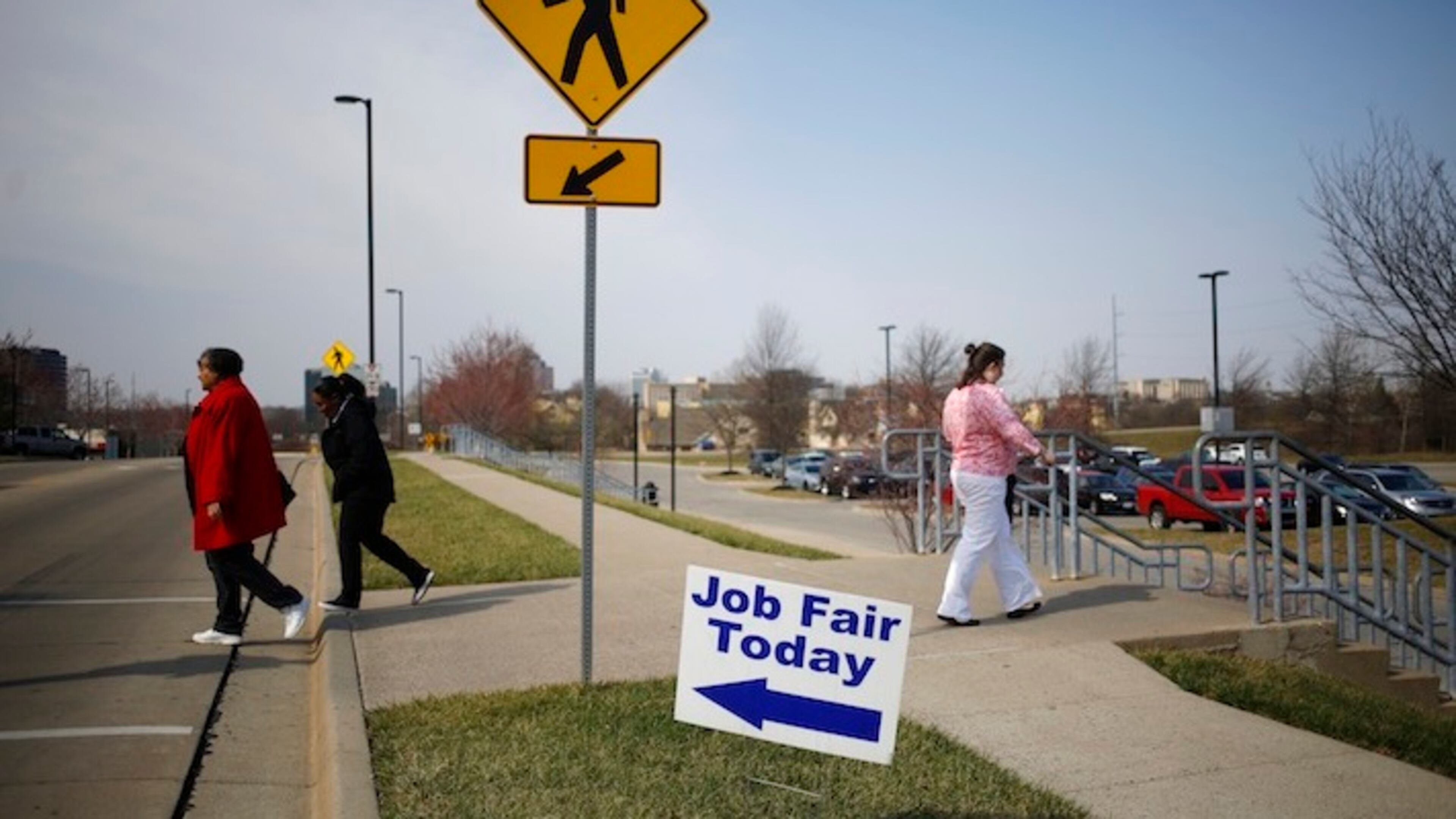 Pedestrians pass in front of signage displayed outside a Job News USA career fair in Overland Park, Kansas, U.S., on March 8, 2017. MUSTS CREDIT: Bloomberg photo by Luke Sharrett.