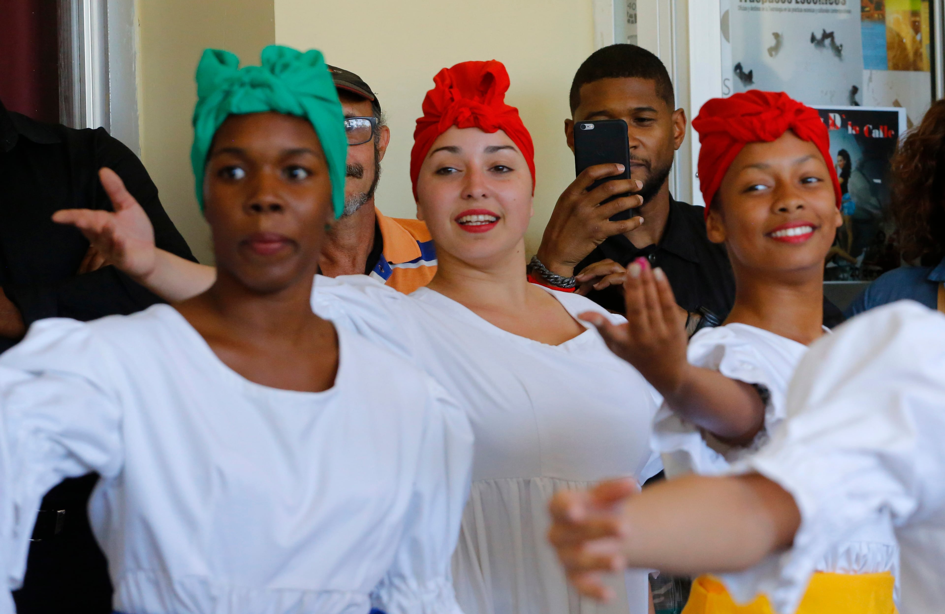 American artist Usher uses his smartphone during a performance by Afro-Cuban dancers at the Arts Institute in Havana, Cuba, Monday, April 18, 2016. The U.S. President's Committee on Arts and the Humanities, including muscians Smokey Robinson, Usher and Dave Matthews, started a four-day visit in Cuba. (AP Photo/Desmond Boylan)