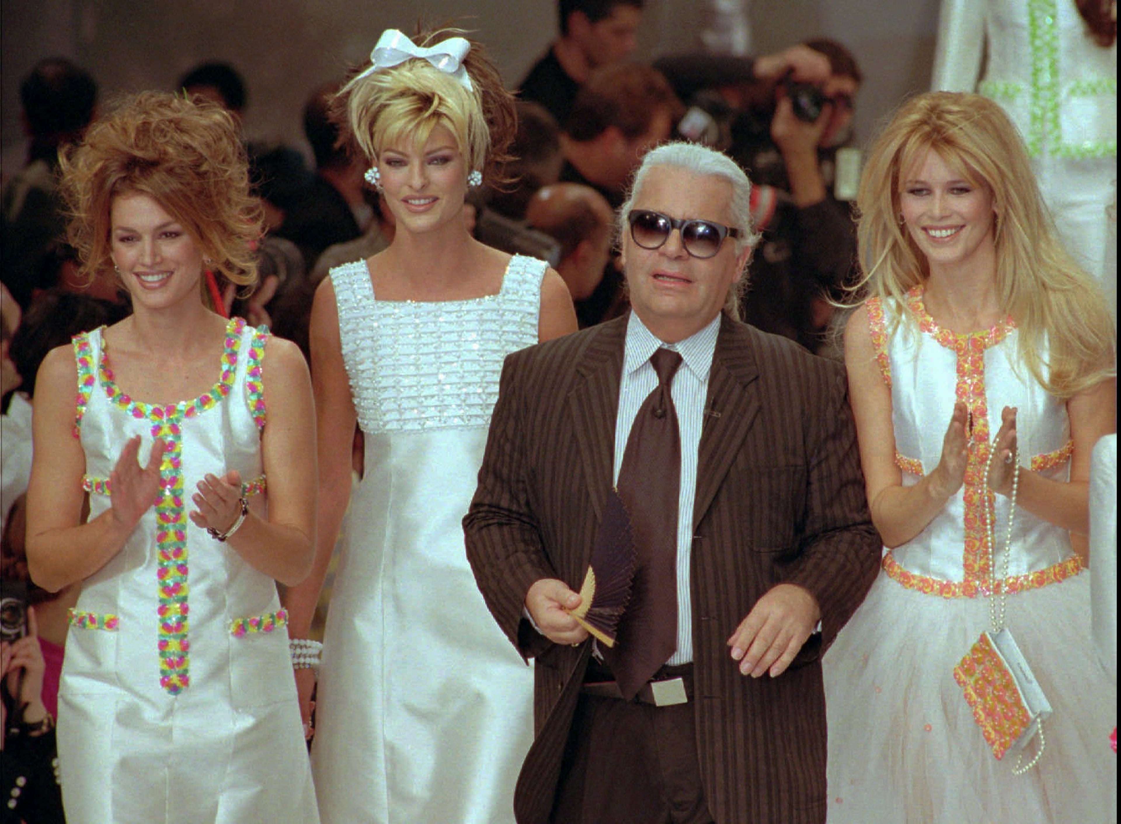 German designer Karl Lagerfeld joins models, from left to right, American Cindy Crawford, Canadian Linda Evangelista and Claudia Schiffer of Germany after the presentation of his 1996 spring-summer ready-to-wear fashion collection for Chanel in Paris, Thursday October 19, 1995.(AP Photo/Remy de la Mauviniere)