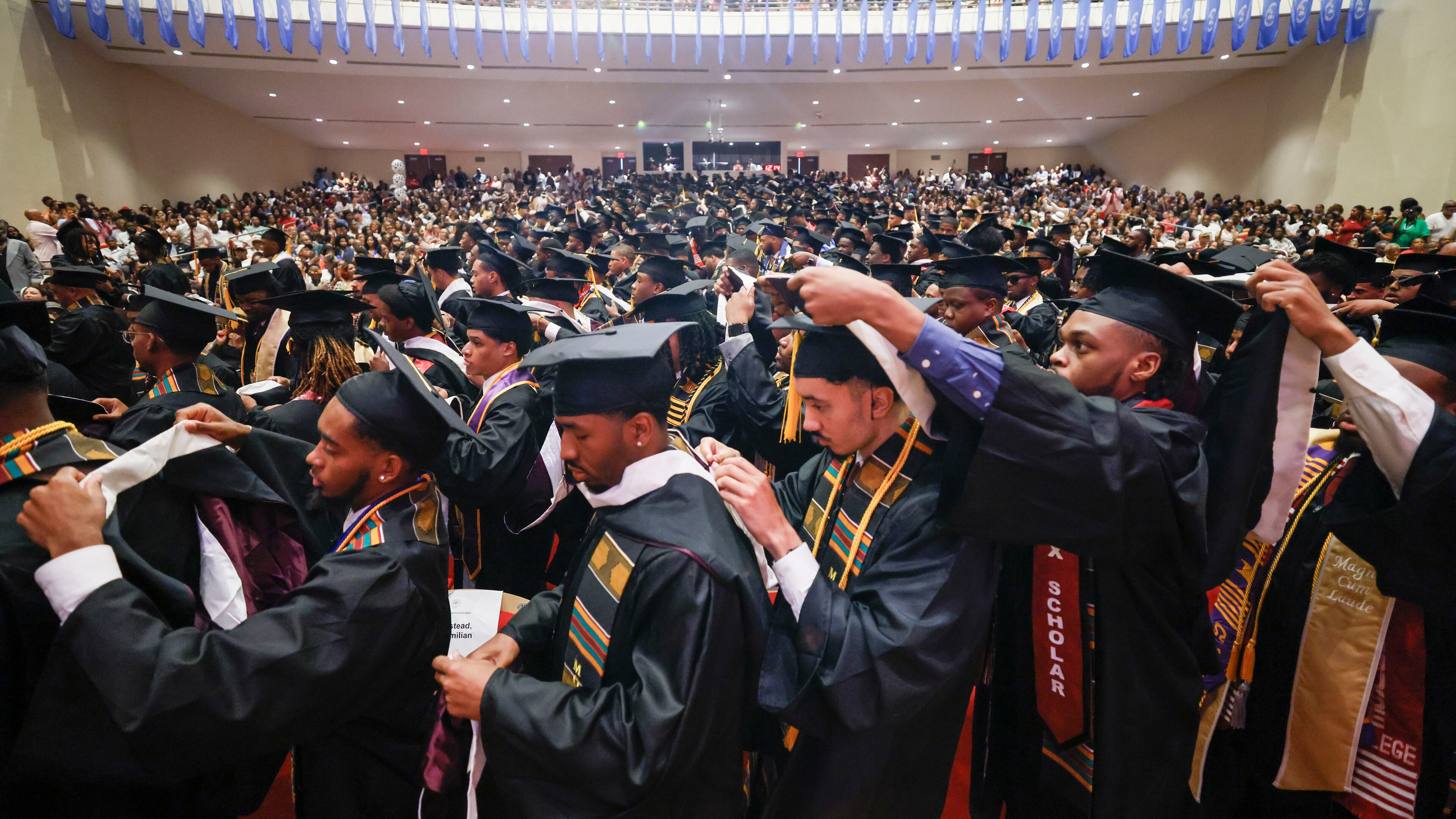 Graduates helped each other don hoods at Morehouse College's 141st Commencement Ceremony on Sunday, May 18, 2025. The historically Black college in Atlanta could have to pay several hundred thousand dollars through a proposal under consideration in Congress. (Miguel Martinez/AJC)