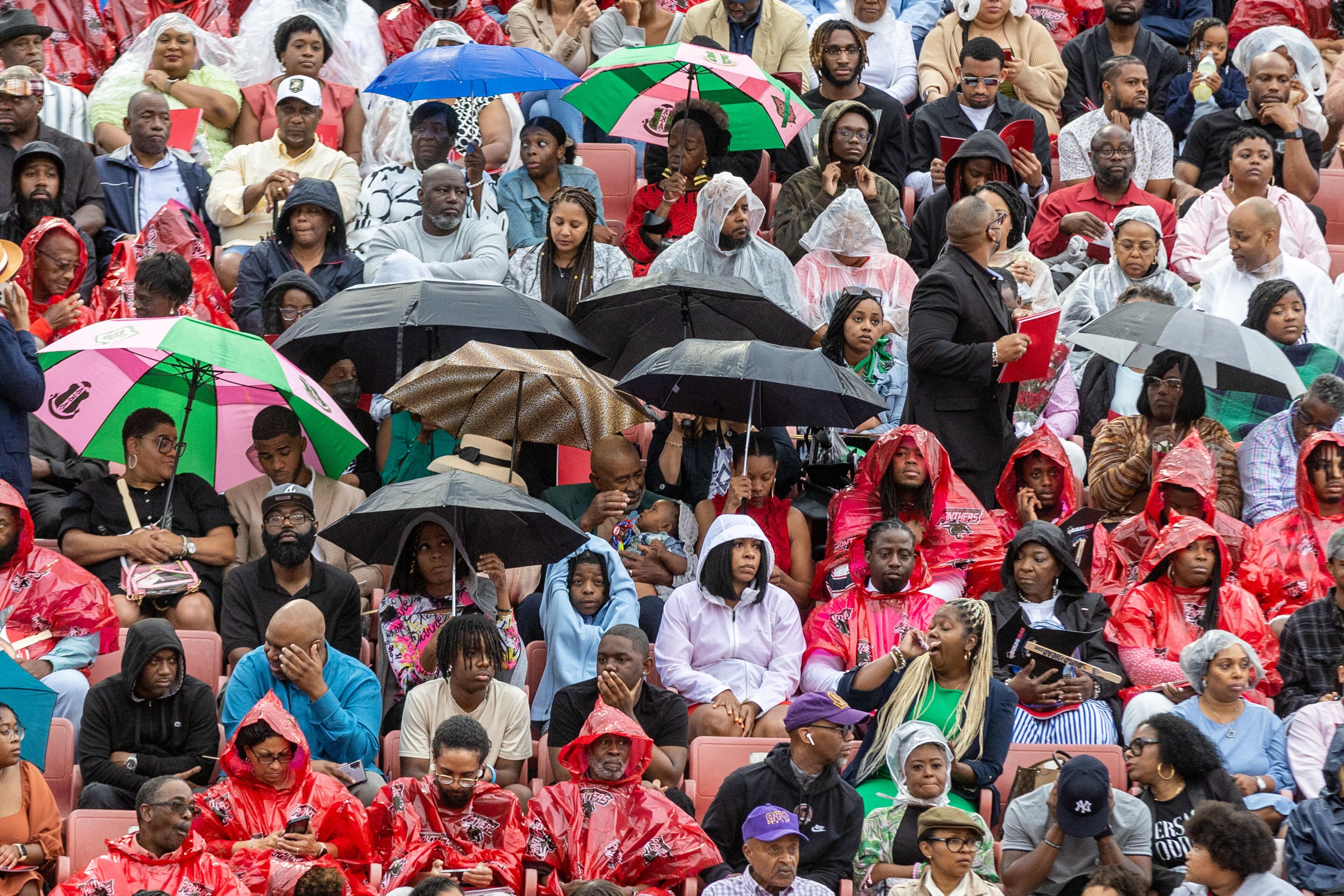 Friends and family try and stay dry in Panther Stadium before the start of Clark Atlanta University's commencement ceremony Saturday, May 20, 2023. (Steve Schaefer / steve.schaefer@ajc.com)