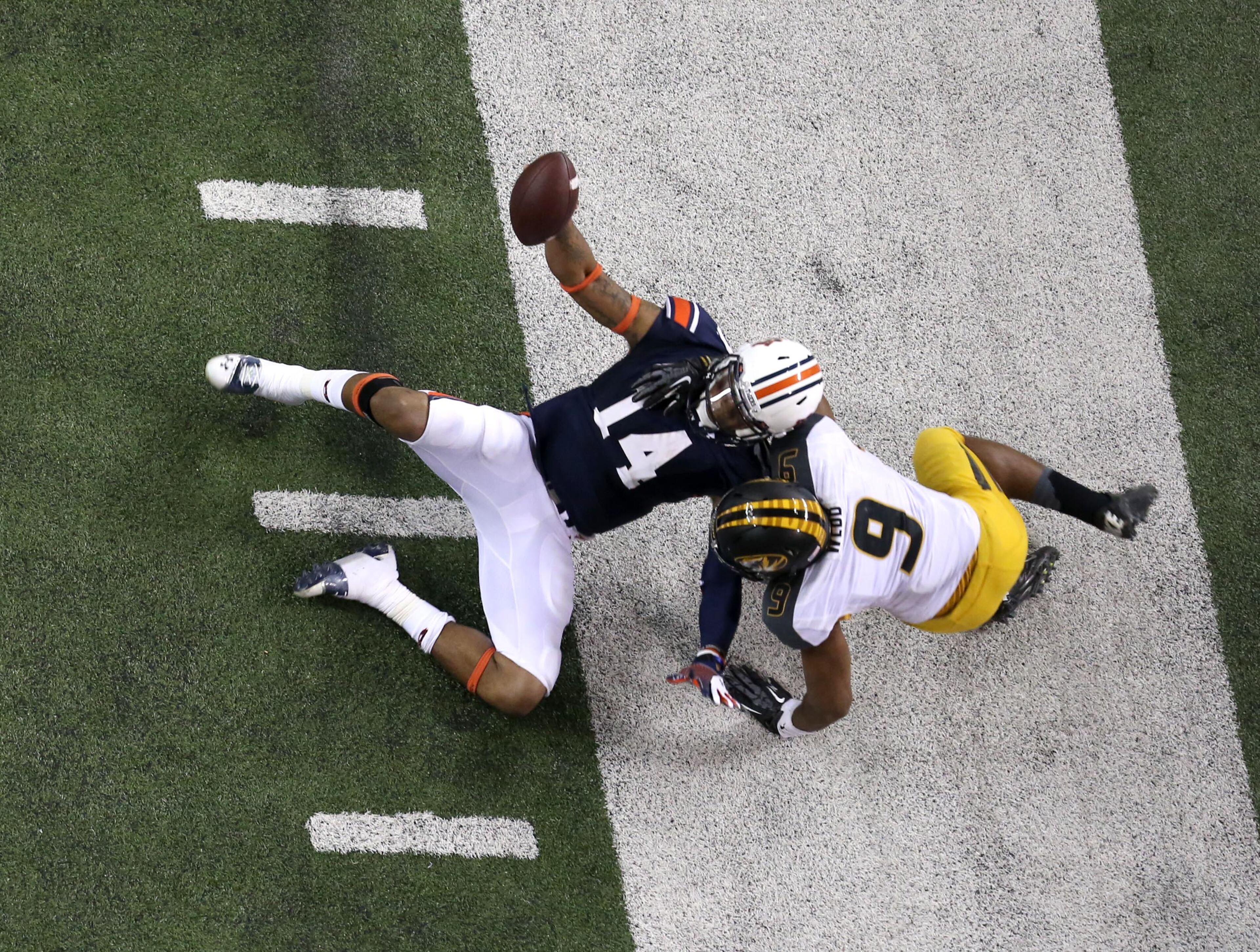 Auburn quarterback Nick Marshall (14) gets dragged out of bounds by Missouri defensive back Braylon Webb (9) after a long run by Marshall in the third quarter of Auburn's 59-42 win over Missouri in the SEC Championship Saturday night in Atlanta, Ga., December 7, 2013. JASON GETZ / JGETZ@AJC.COM