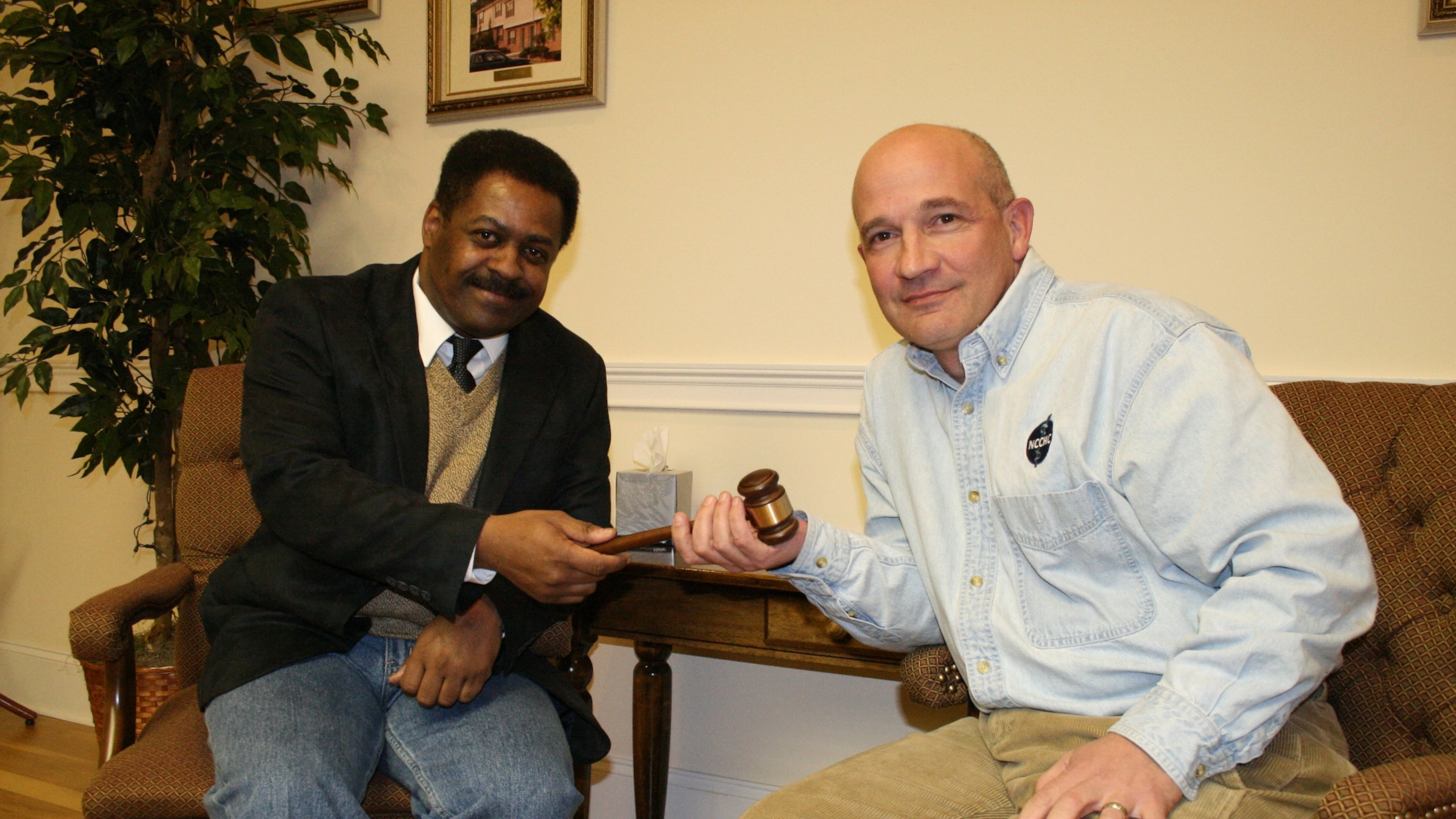 February 2010: Dr. Carlo Musso (right), then-outgoing chairman of the Housing Authority of Clayton County and the proprietor of a jail medical services company, hands the gavel to his successor, James Searcy. Musso recently purchased a former Georgia state prison for $50,000 -- half its appraised value -- in what one competing business believes is a sweetheart deal with the state Department of Corrections.